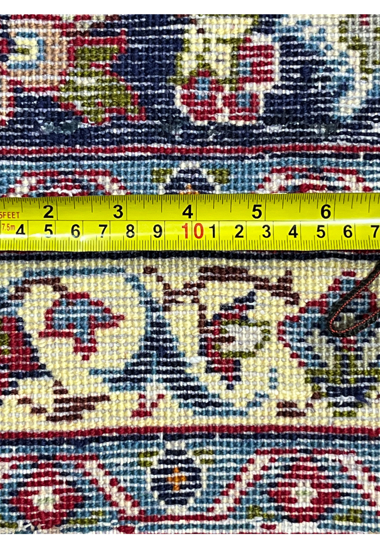Back of the rug with a tape measure documenting the fine knot count across the cotton foundation