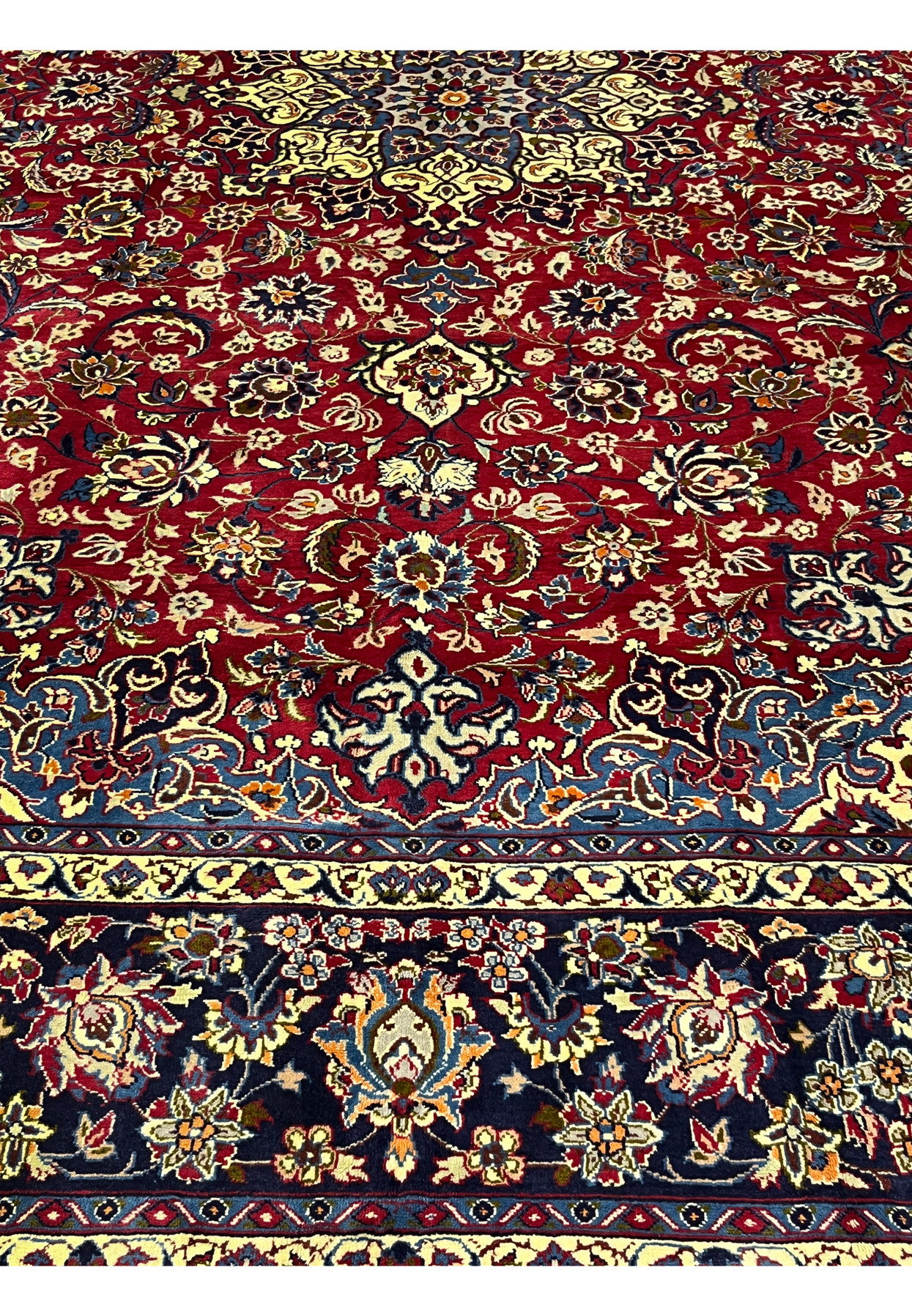 Lower border of the carpet showing the repeating floral palmette motif on a dark indigo ground