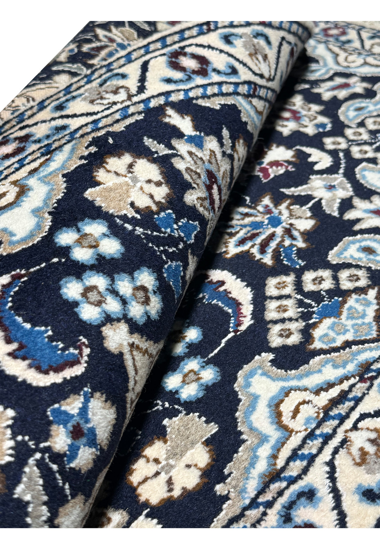 Rolled Persian Nain rug revealing its dense fine pile and cool navy and ivory palette