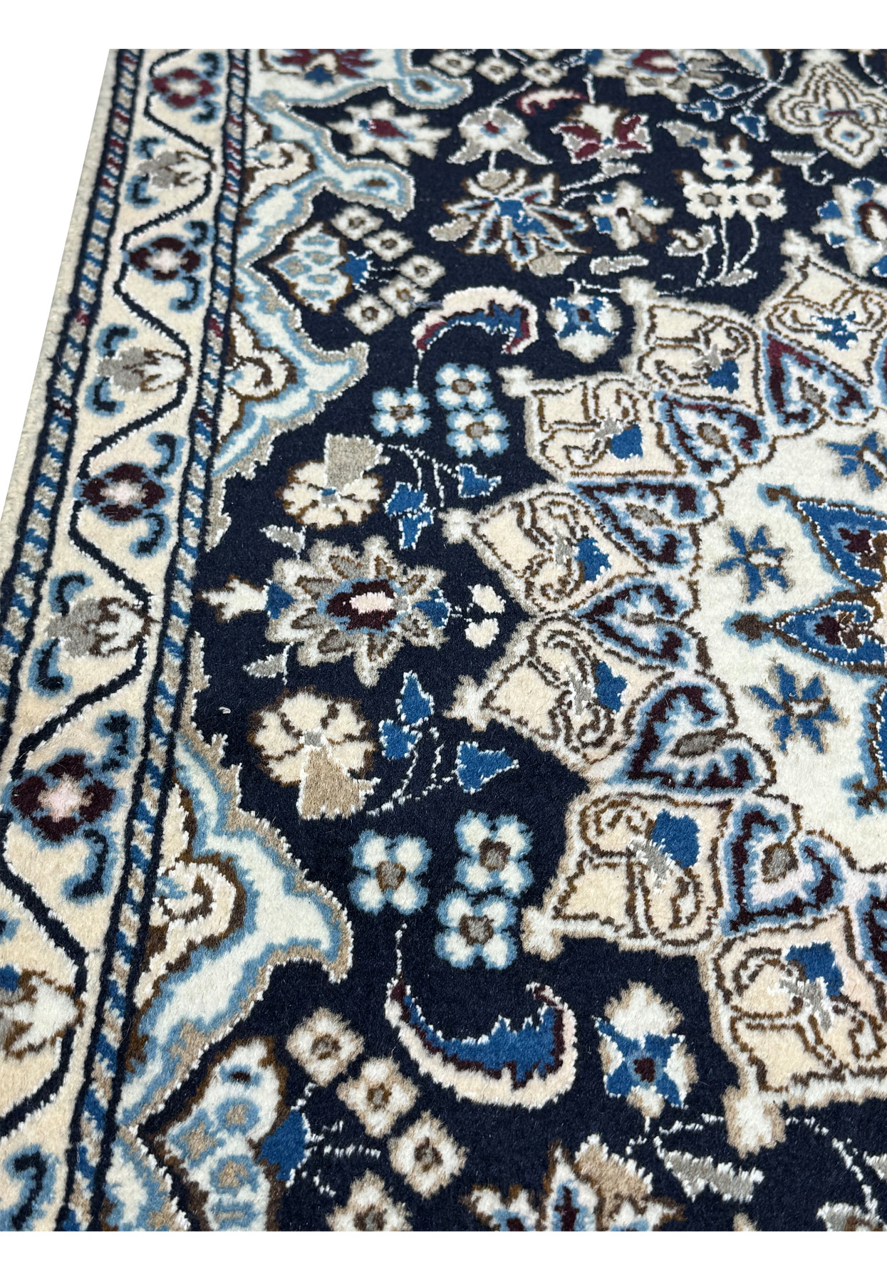 Close-up of fine Nain knotting showing small blossoms and arabesques in blue, ivory, and wine