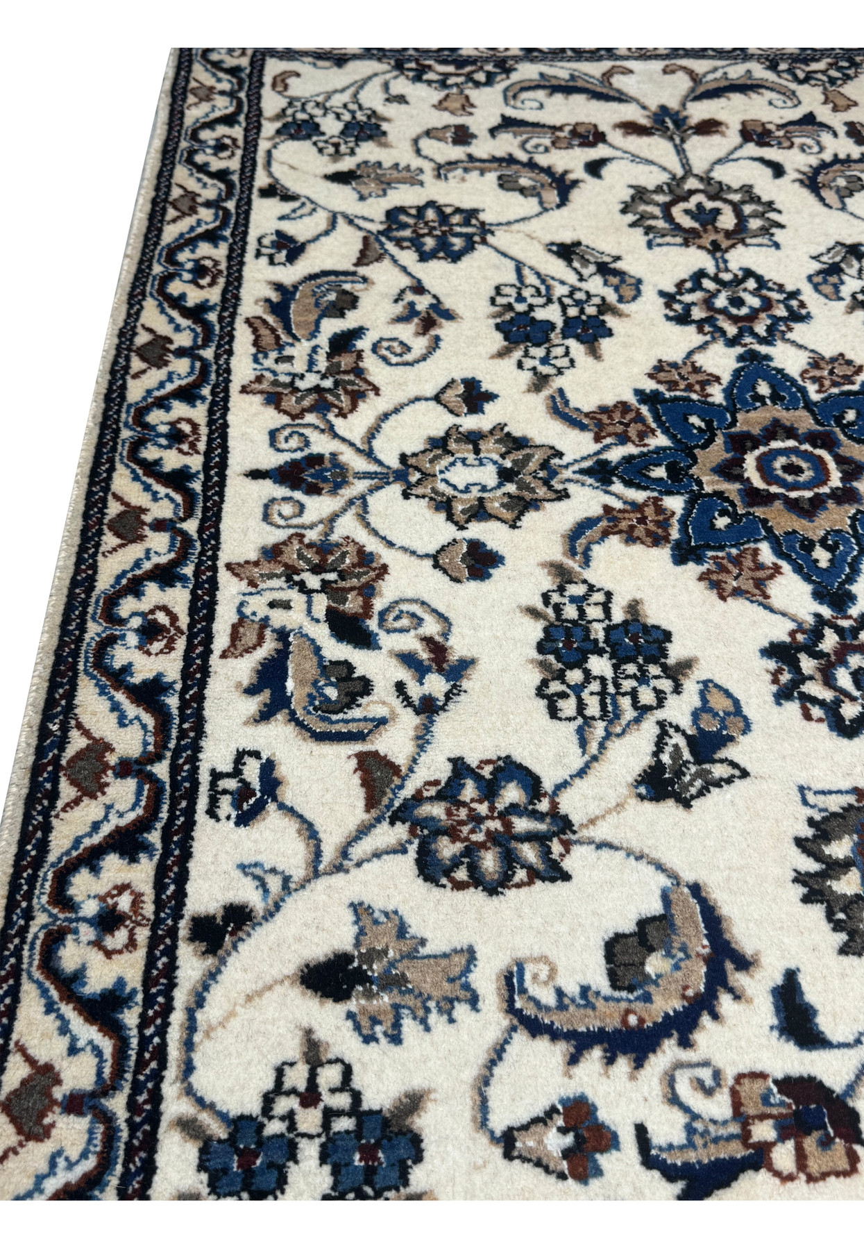 Angled view of the ivory Nain rug showing its allover floral pattern and fine wool pile