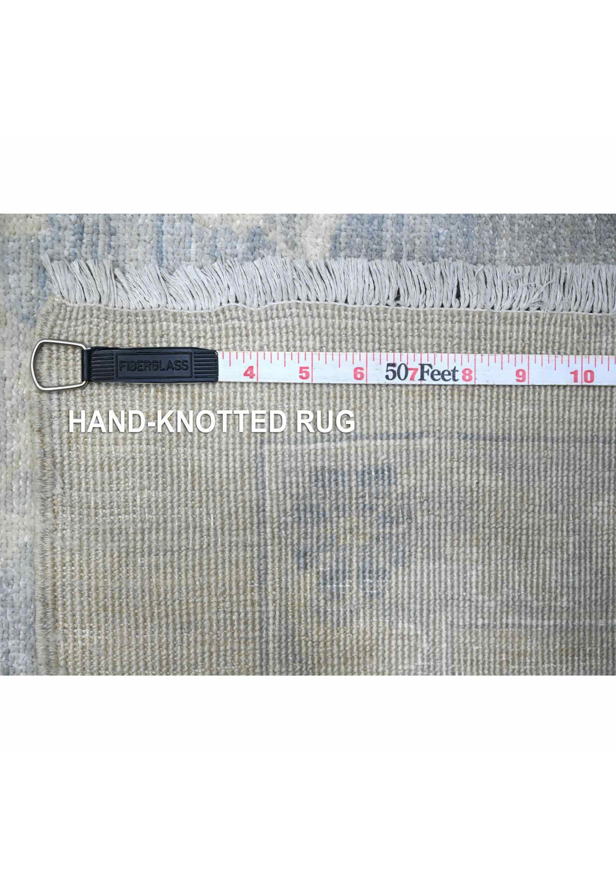 Reverse of the Peshawar measured against a tape, showing the hand-knotted density on cotton