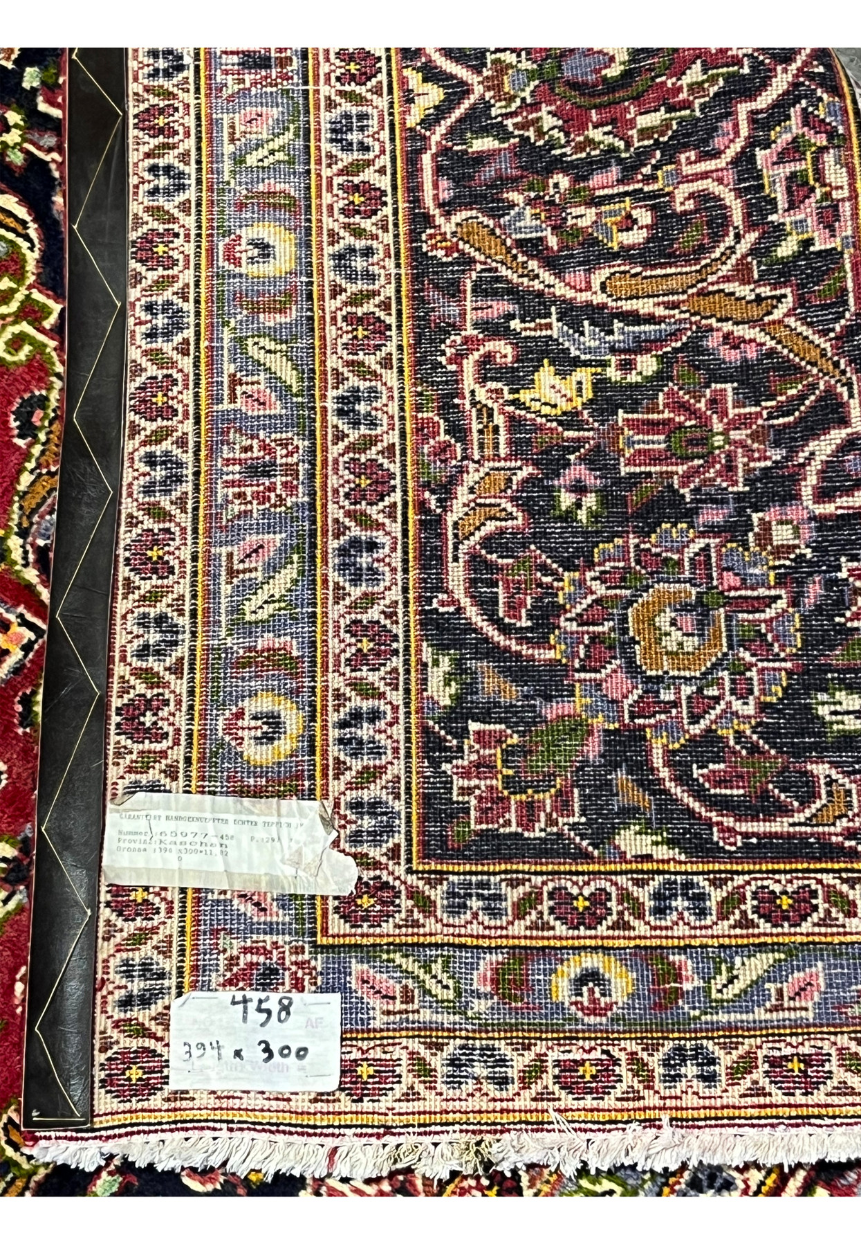 Reverse of the rug with the original Kashan dealer tag and visible hand-tied knots.