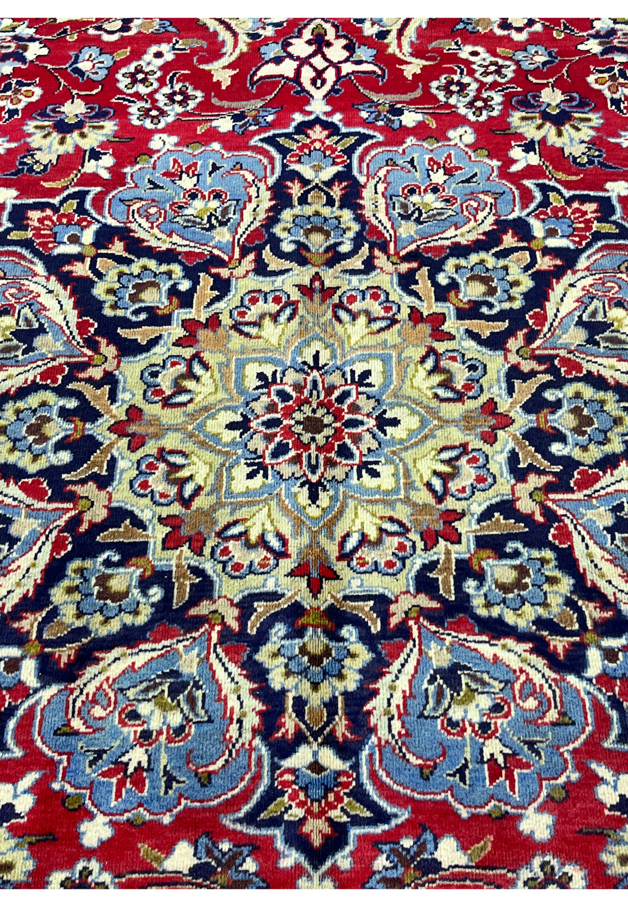 Close detail of the medallion core in cream, blue, and red on the crimson Najafabad field.