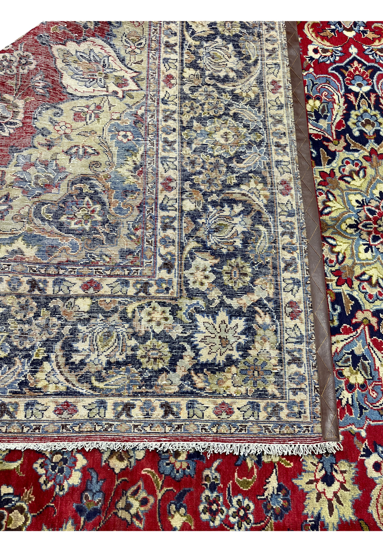 Folded back corner of the rug revealing the tight foundation weave and navy border reverse.