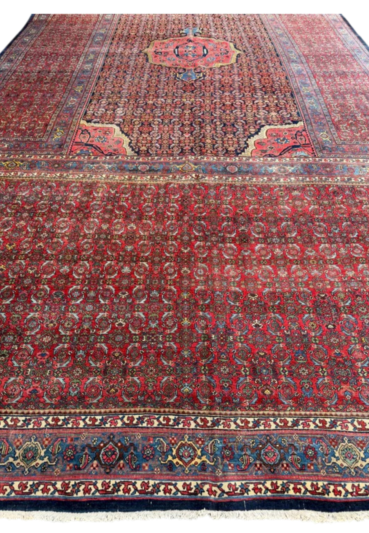 Palace-size antique Bijar rug laid flat, showing red field, medallion and layered borders