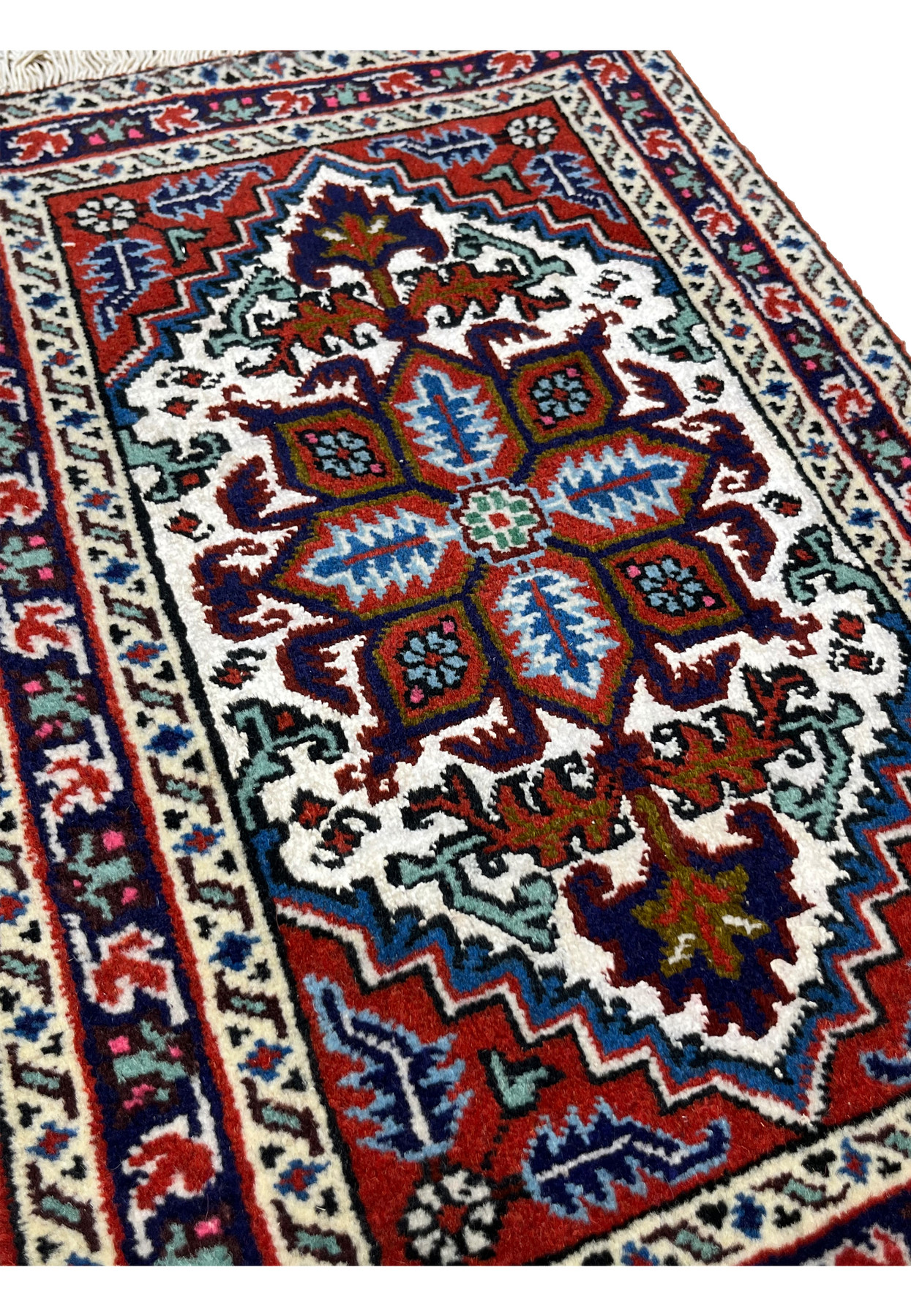 Angled view of small Ardebil rug showing silk highlighted details and ivory vine border
