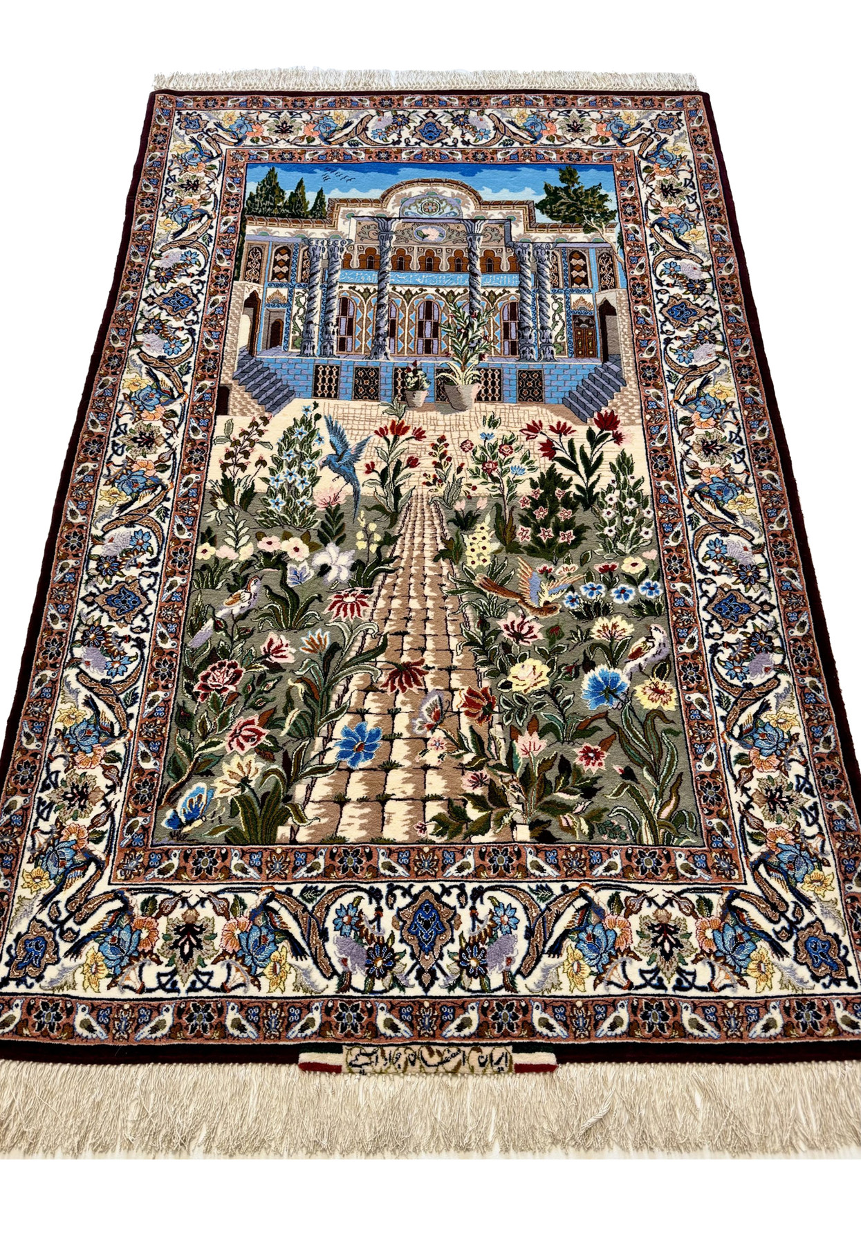 Persian Isfahan garden rug laid flat showing full courtyard scene and ivory silk fringe