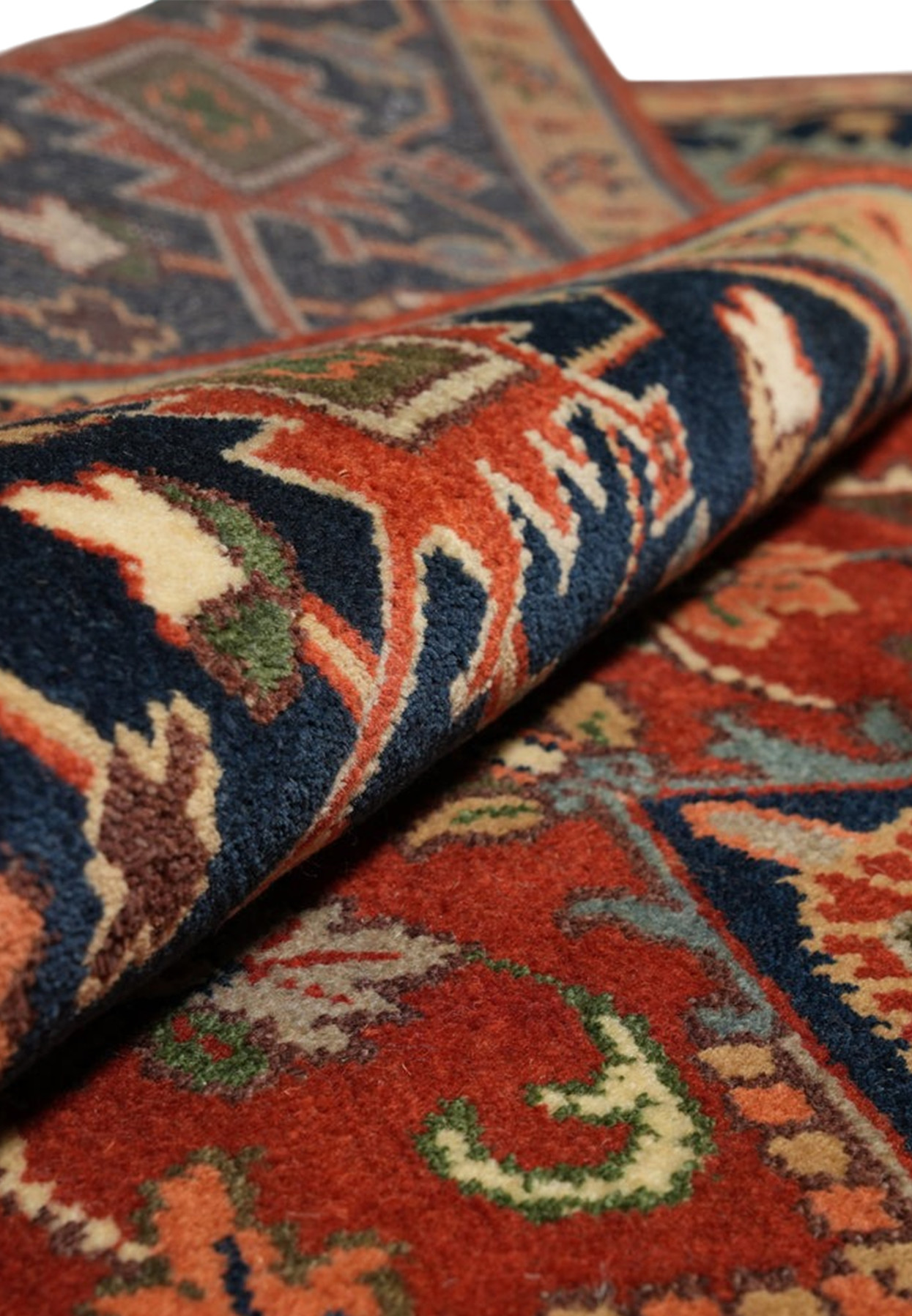 Rolled square Heriz rug showing plush wool-look pile in rust, navy and ice blue