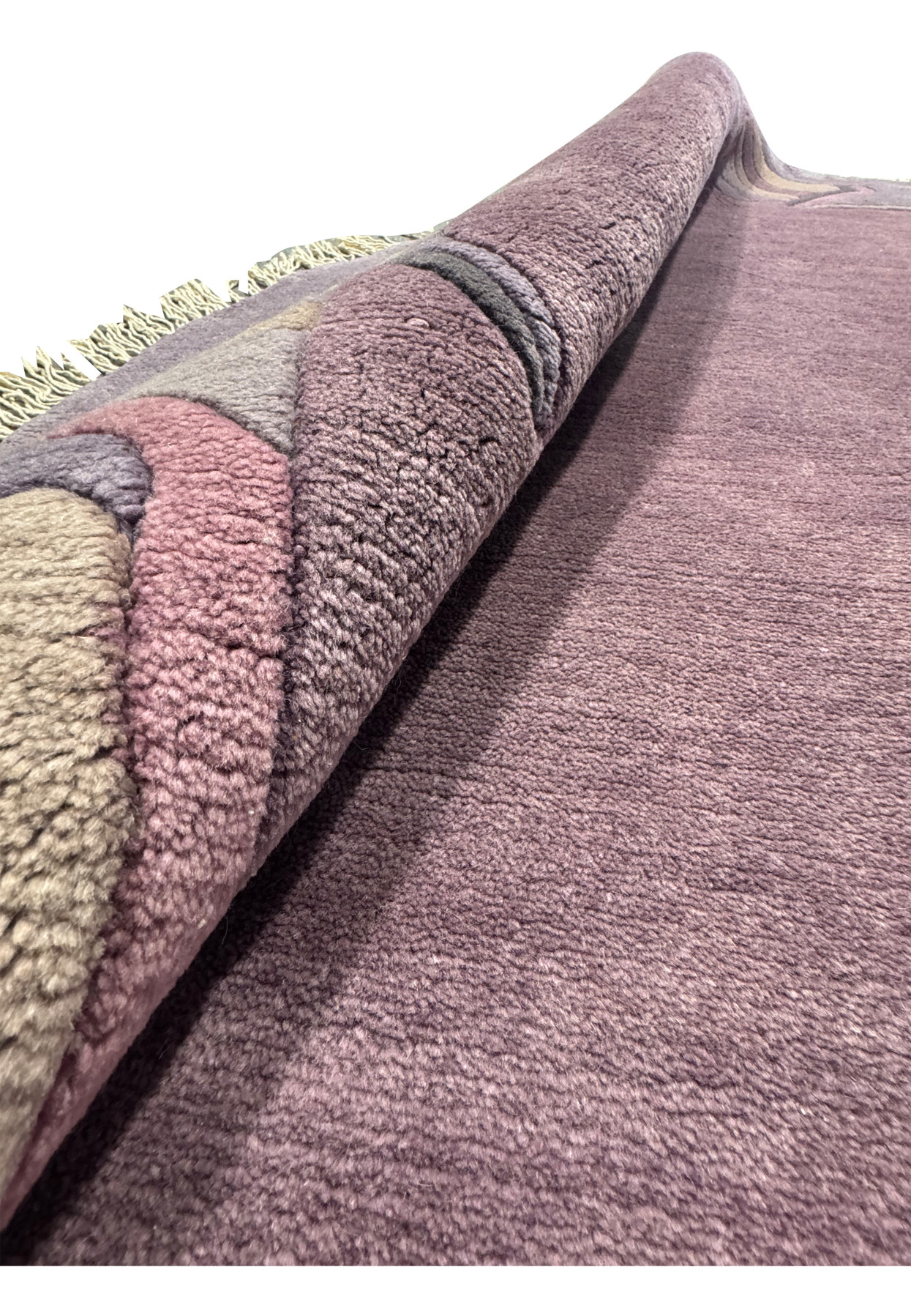 Rolled corner of the round Nepali rug revealing dense wool pile and dusty purple selvage