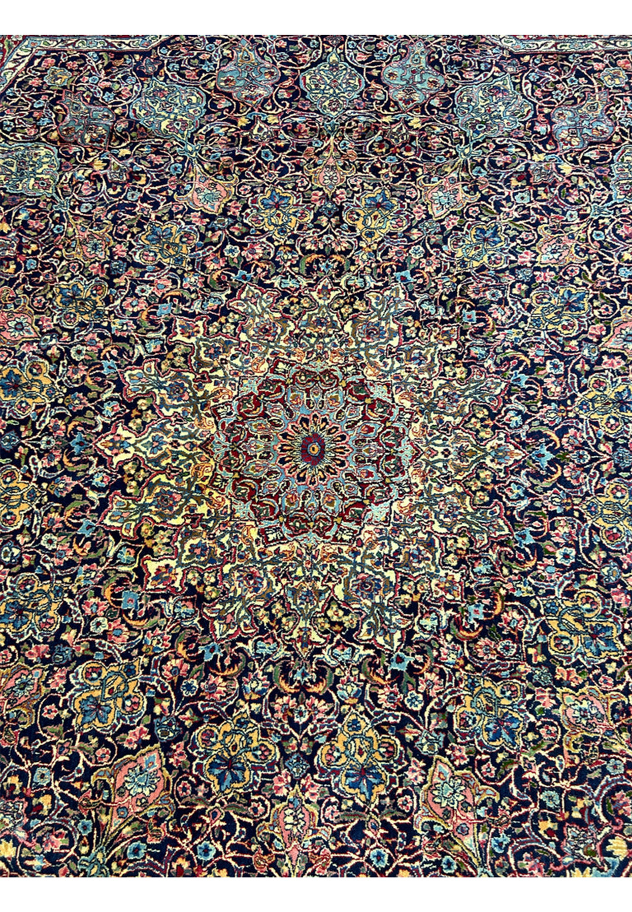 Many-pointed star medallion radiating across the dark navy field of this antique rug