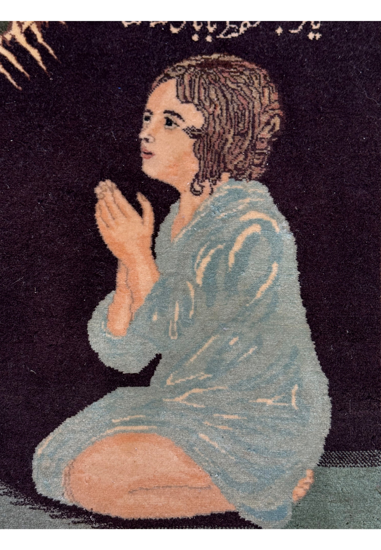 Close-up of praying girl woven in wool with lifelike face and light blue robe
