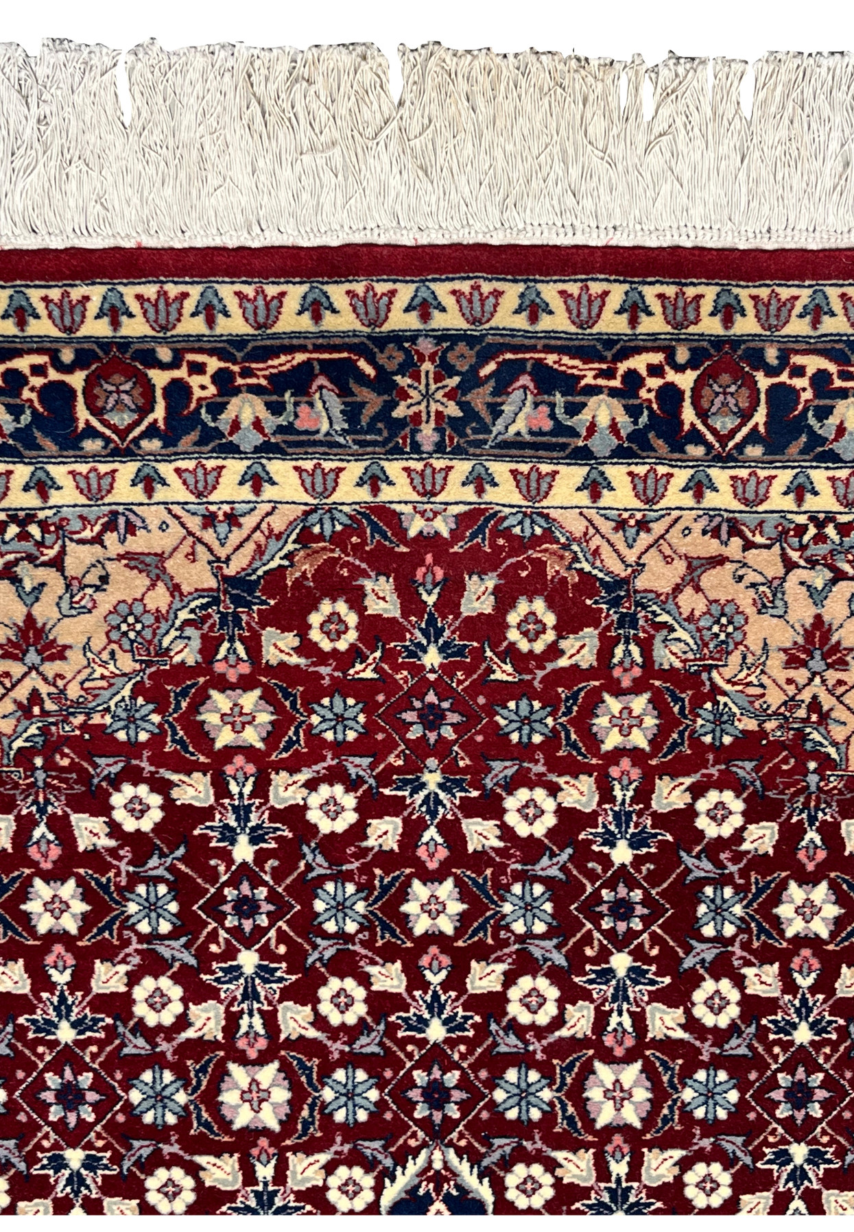 Upper border detail of a Persian Tabriz rug highlighting ivory framing, navy vine motifs, fine floral elements, and precise hand knotted craftsmanship