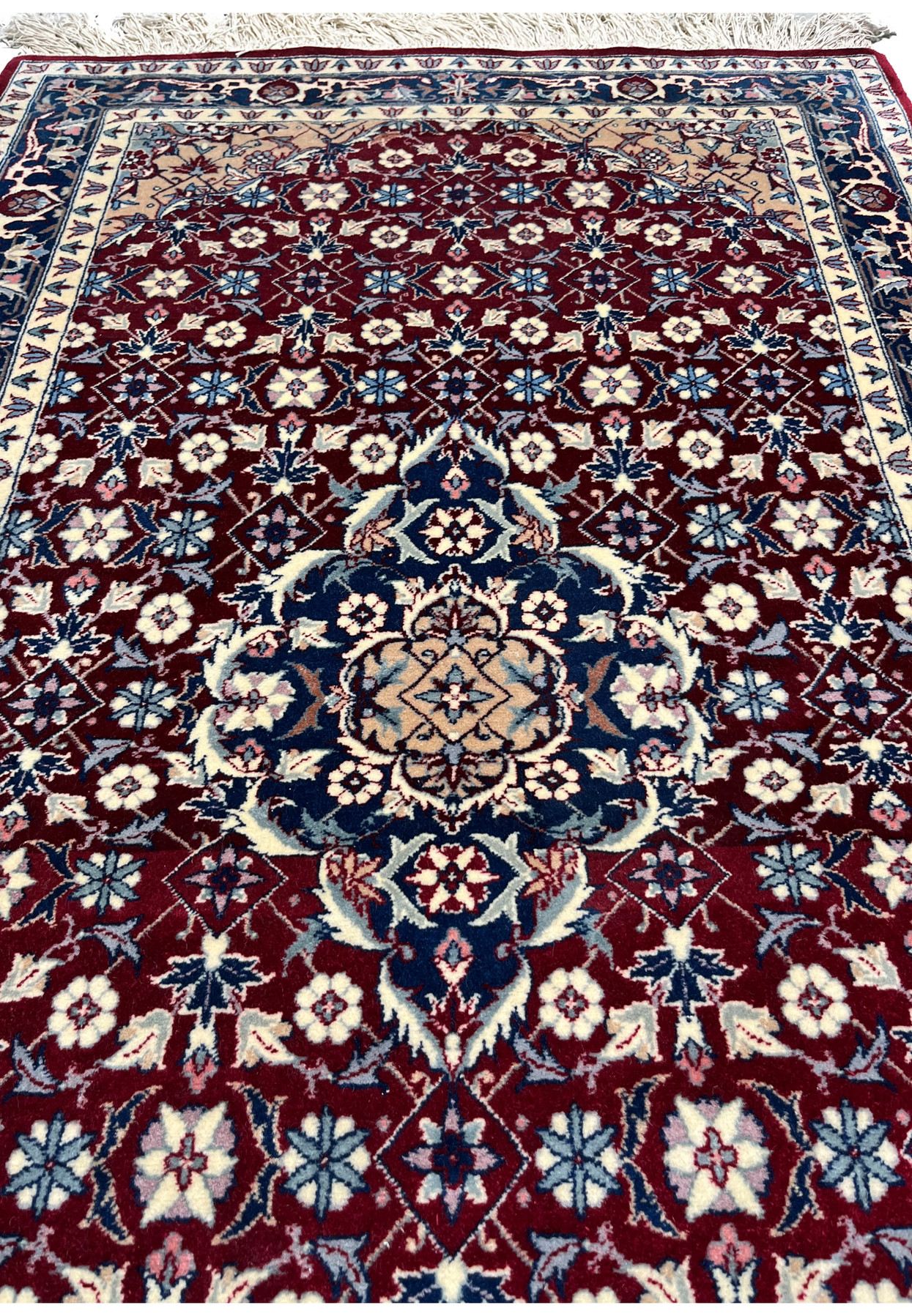 Midfield close up of a Persian Tabriz rug showing repeating floral lattice, crisp knot work, rich ruby background, and subtle color transitions