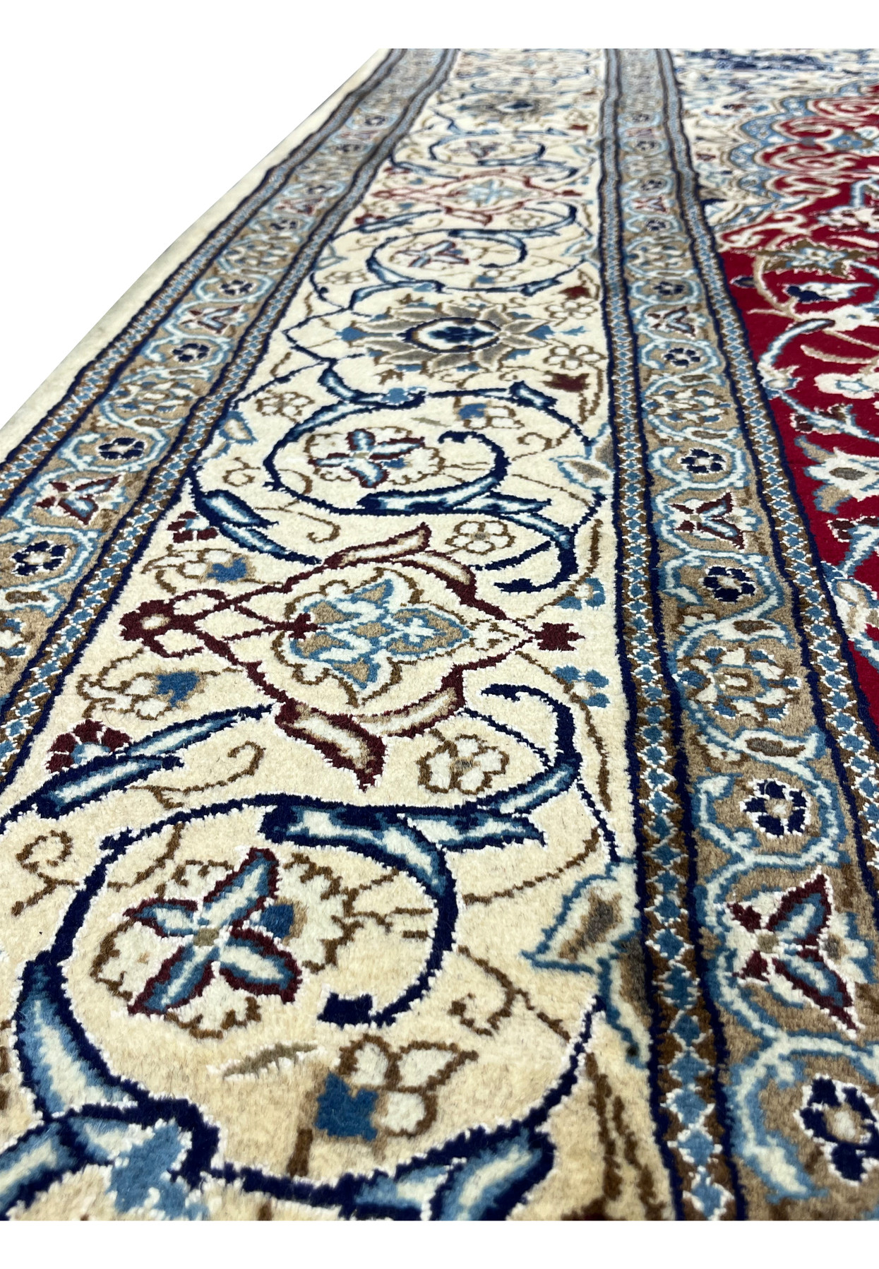 Border close-up of Persian Nain rug highlighting ivory ground, scrolling vines, and navy floral elements