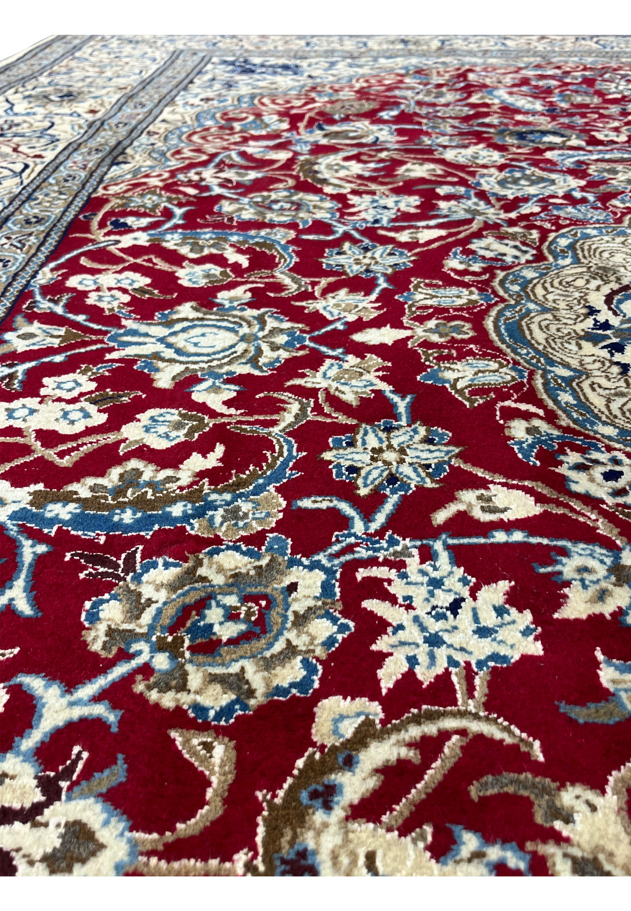 Floral motif close-up on red Persian Nain rug with crisp outlines and balanced navy and ivory accents