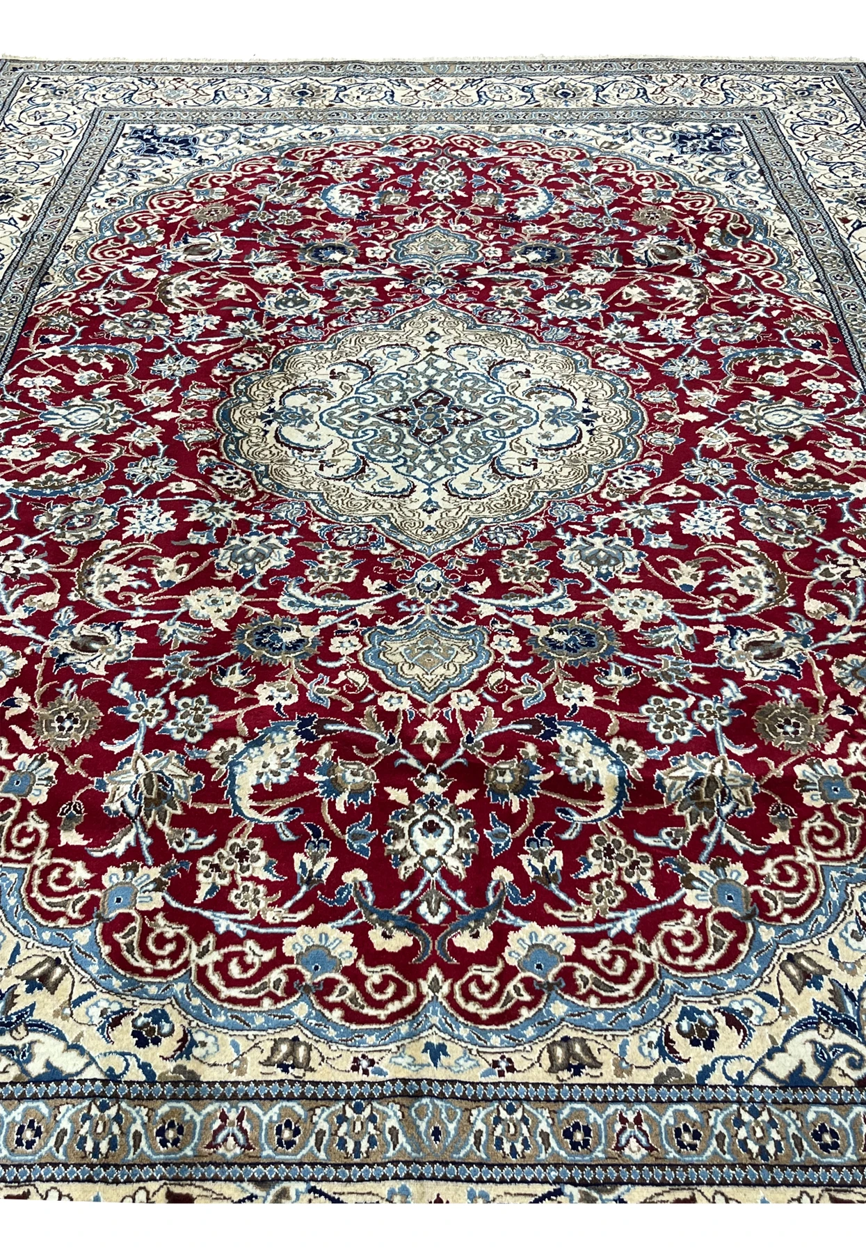 Midfield detail of red Persian Nain rug with dense floral vines, silk highlights, and precise hand knotted pattern