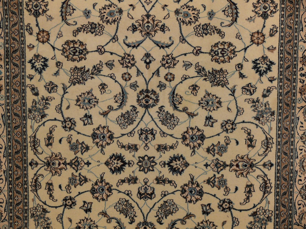 Close-up of floral vine in sky blue and turquoise on beige Persian Nain rug