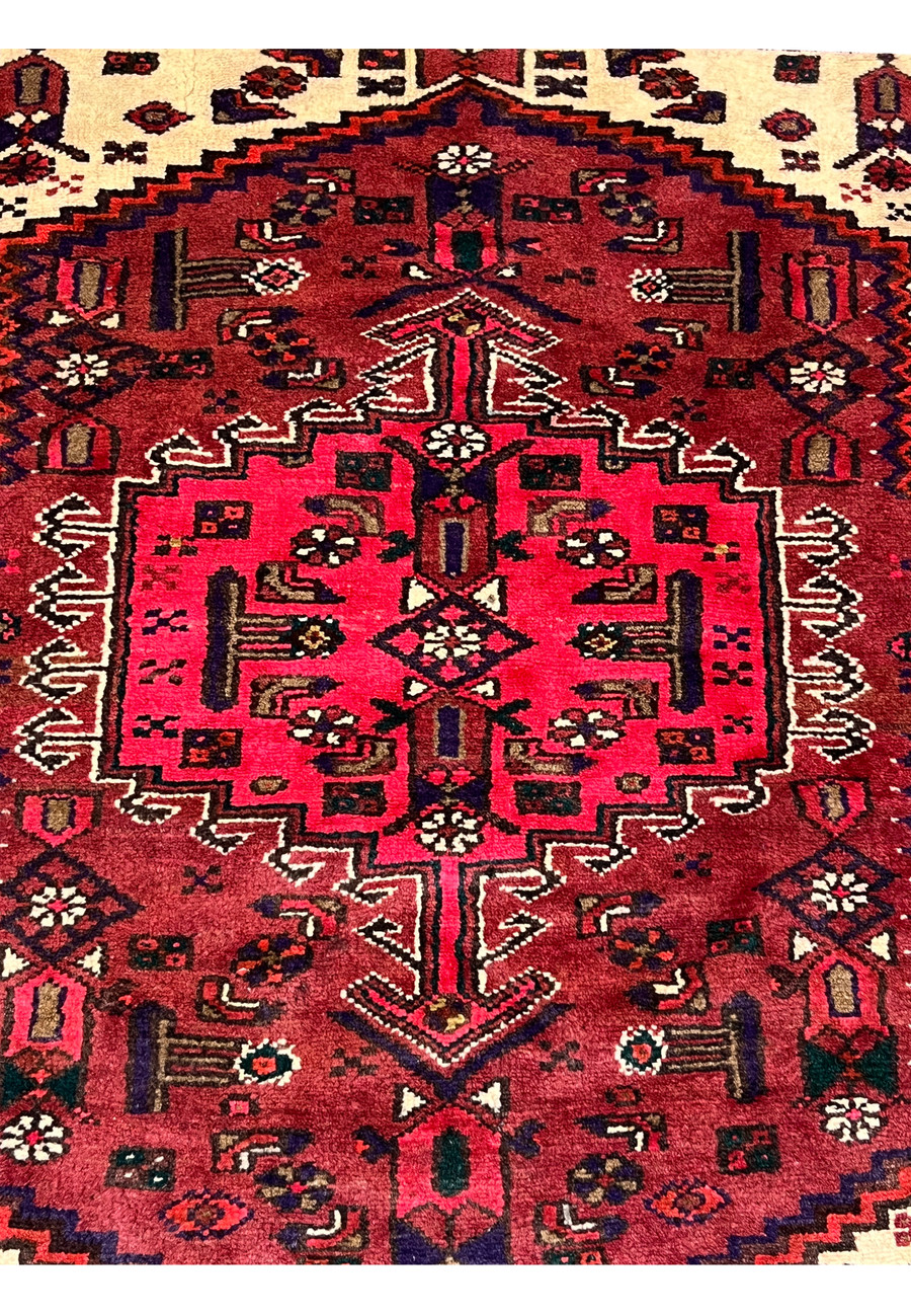 Close-up of the central medallion on an antique Persian Hamedan rug, highlighting bold geometric forms, rich crimson tones, and tribal weaving precision