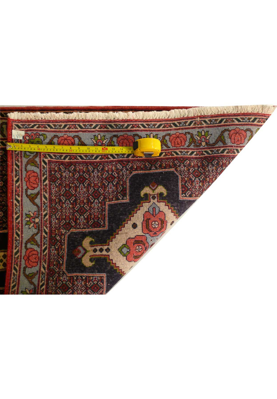 A close-up of a Persian Senneh runner with an intricate border design in shades of navy blue and rust, woven from high-quality wool.