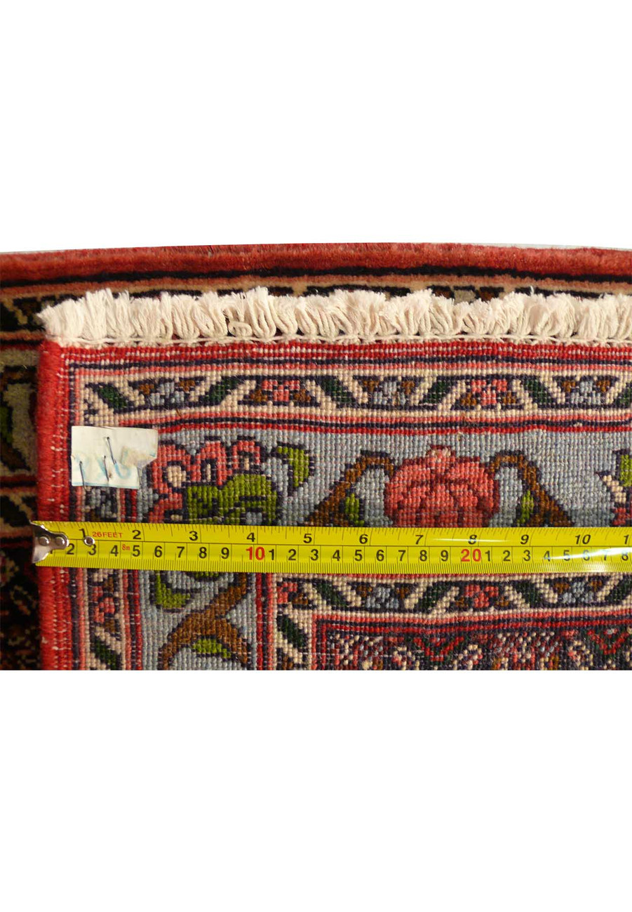 A vintage Persian Senneh runner with a faded geometric pattern in earthy tones of brown, beige, and green, adding character to a rustic decor.