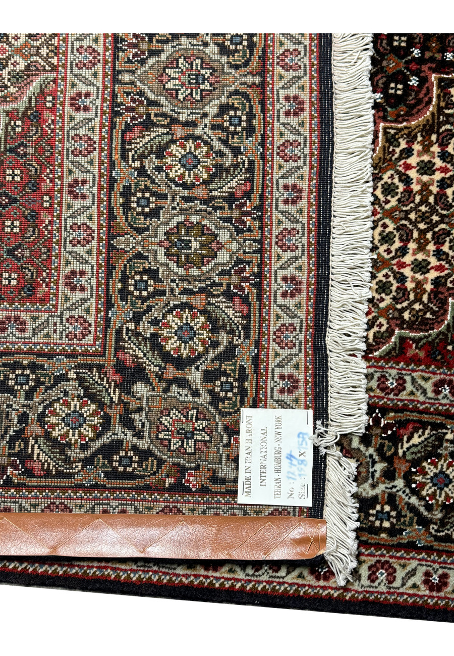 "Persian Tabriz Mahi rug edge detailing, showcasing the fine weave and complex designs in beige, red, and navy on a dark background.