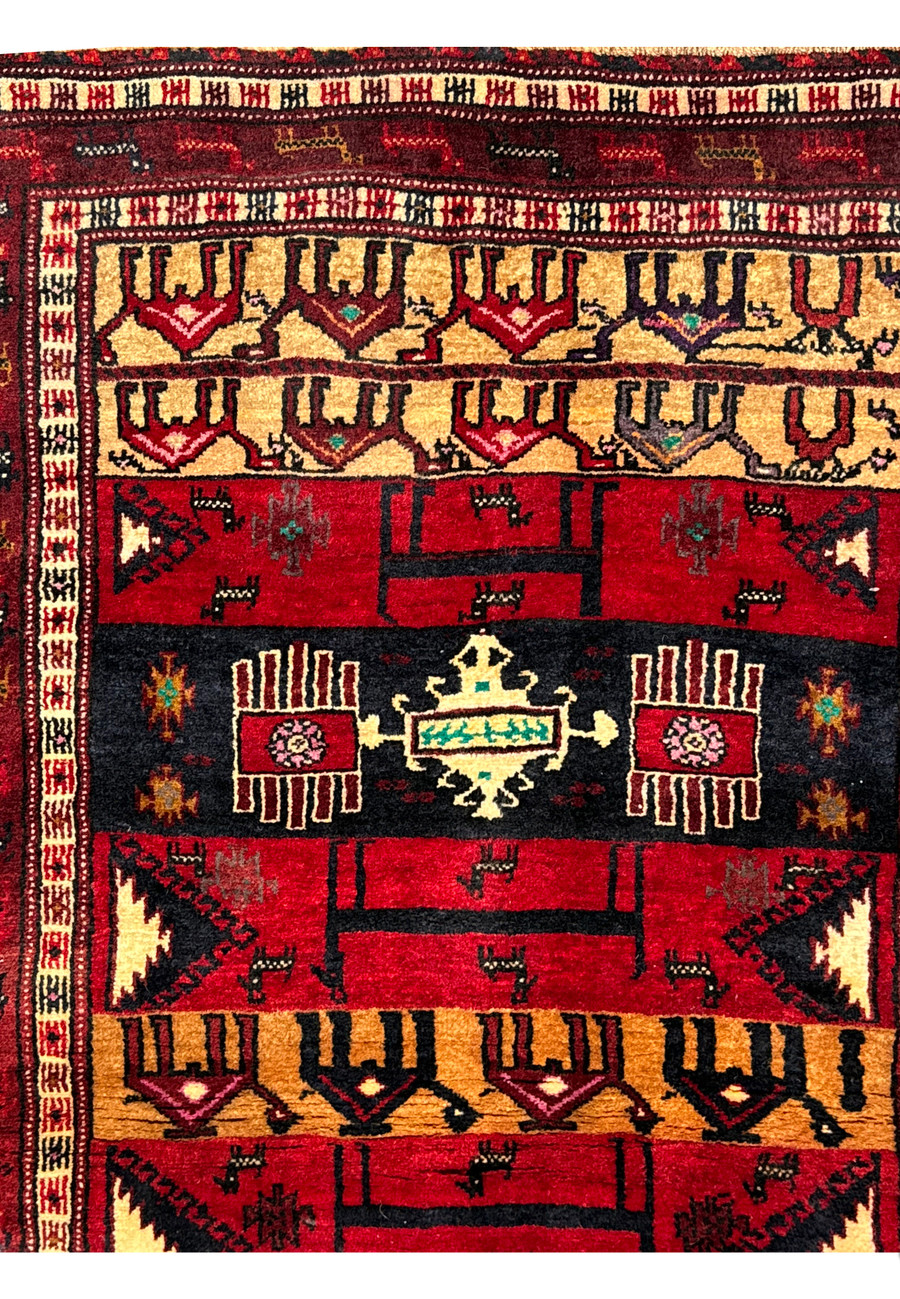 Detailed view of the upper portion of a Persian Baluch rug, with colorful tribal patterns and traditional symbols