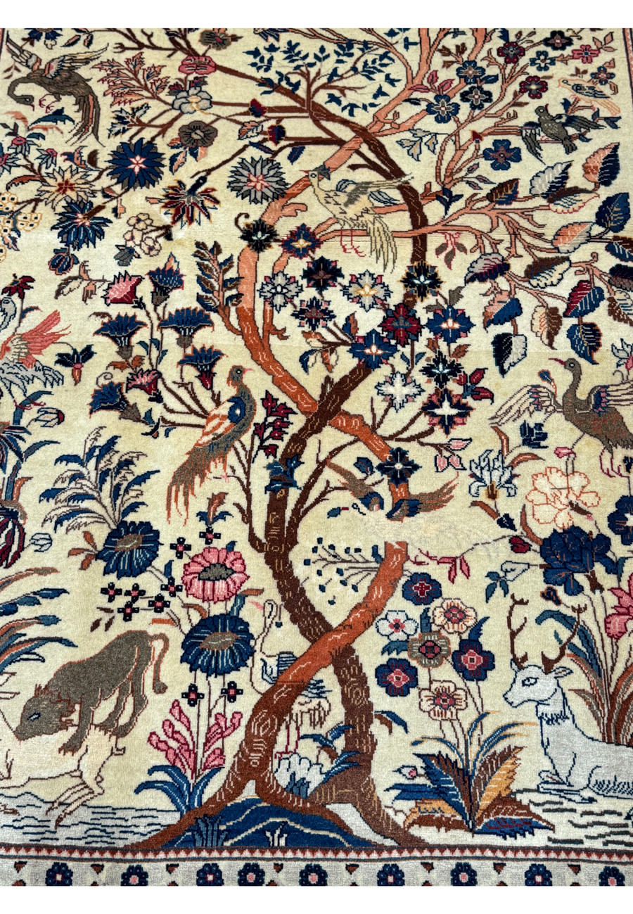Close-up of the central Tree of Life design on an Antique Persian Kashan rug, highlighting the intertwined branches with birds and wildlife motifs on a cream background