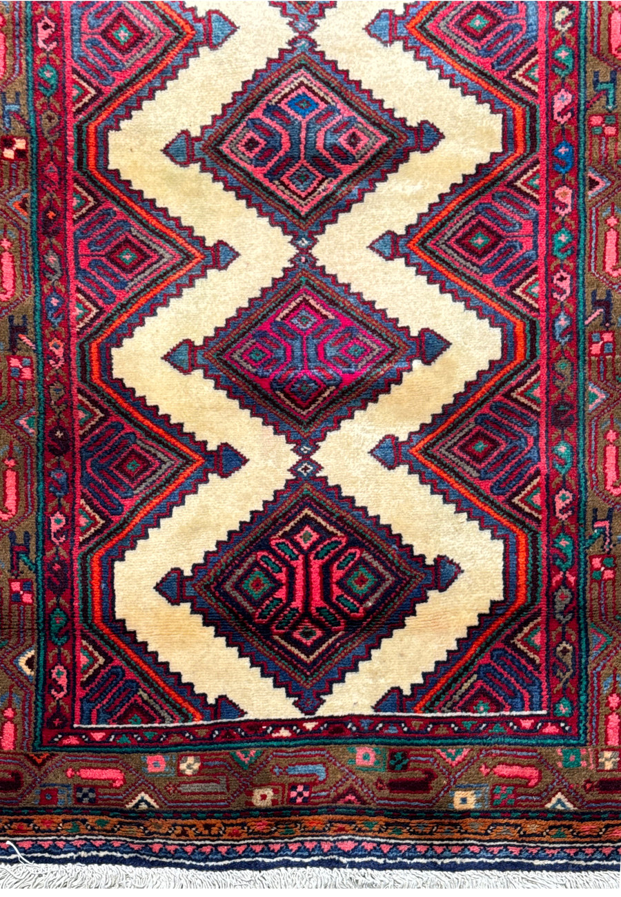 Close-up view of a Persian Hamedan runner rug showcasing diamond motifs and intricate border designs