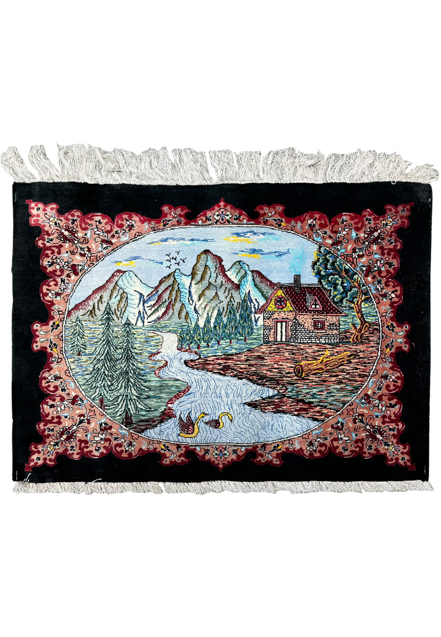 Detailed view of a hand-knotted Persian Qum silk rug displaying a central landscape scene with mountains, a river, and a cottage