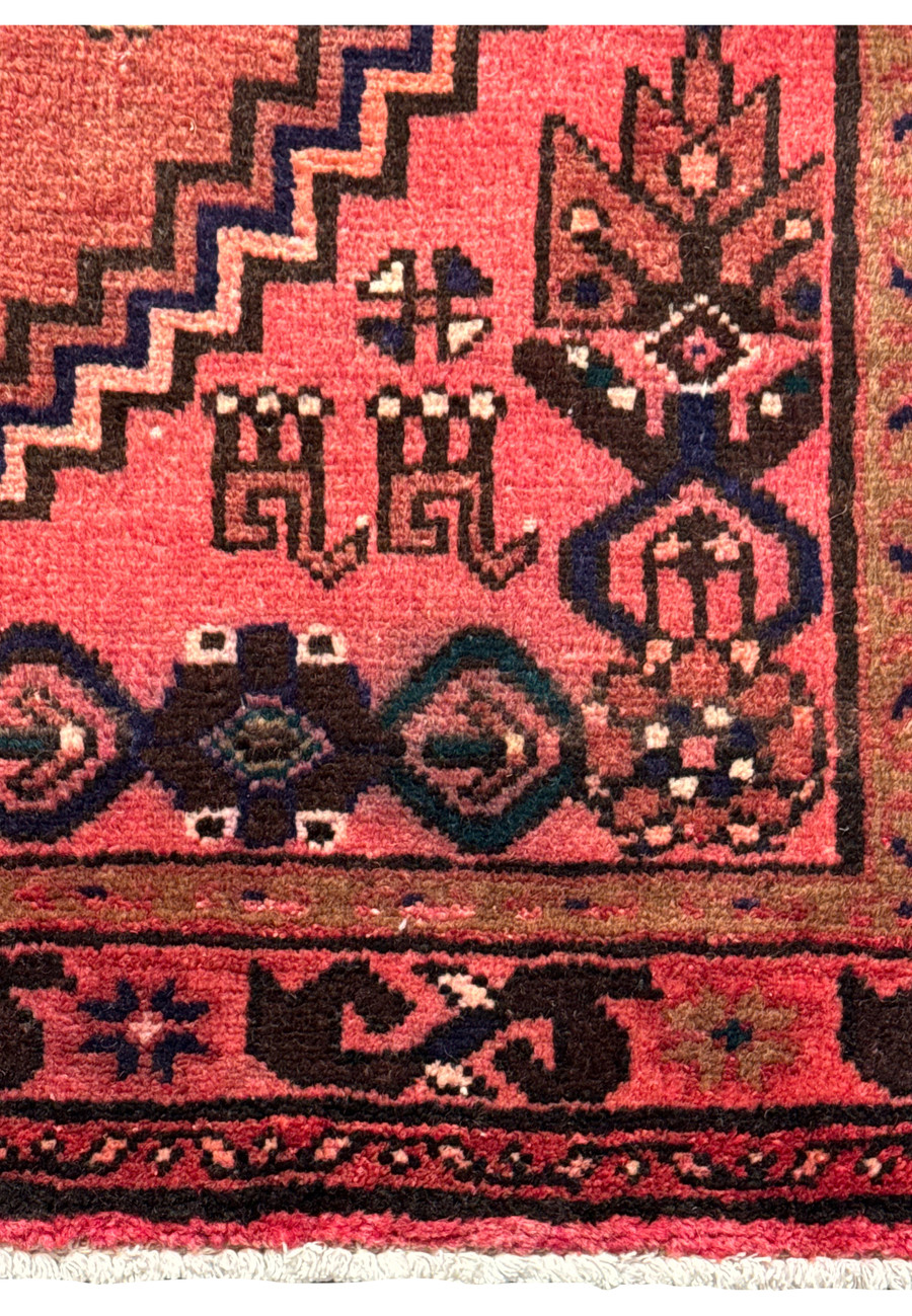 Elevated edge view of the Persian Baluch rug, emphasizing the detailed border patterns and fringe