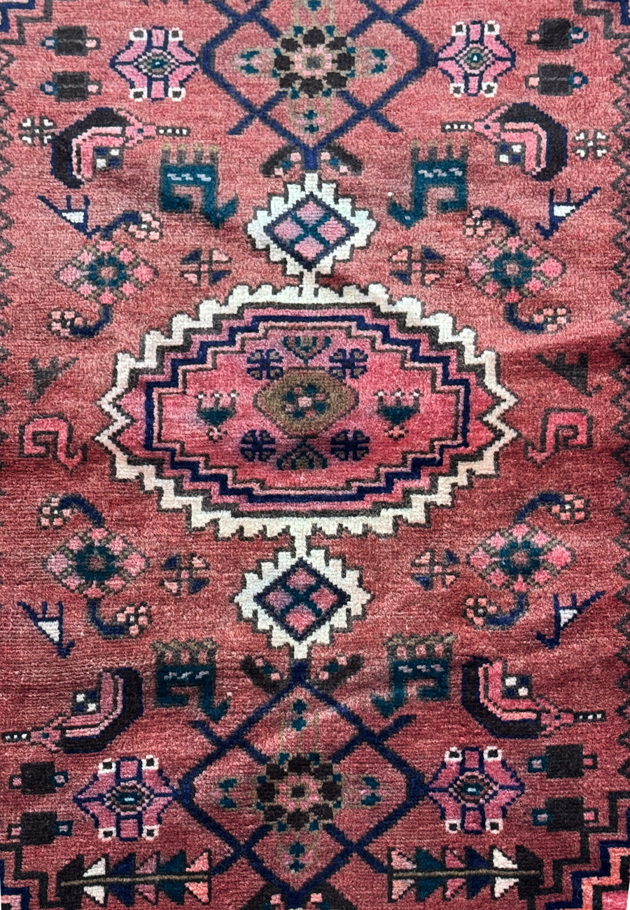 Close-up of the central medallion on a Persian Baluch rug, detailing the intricate patterns and symbols