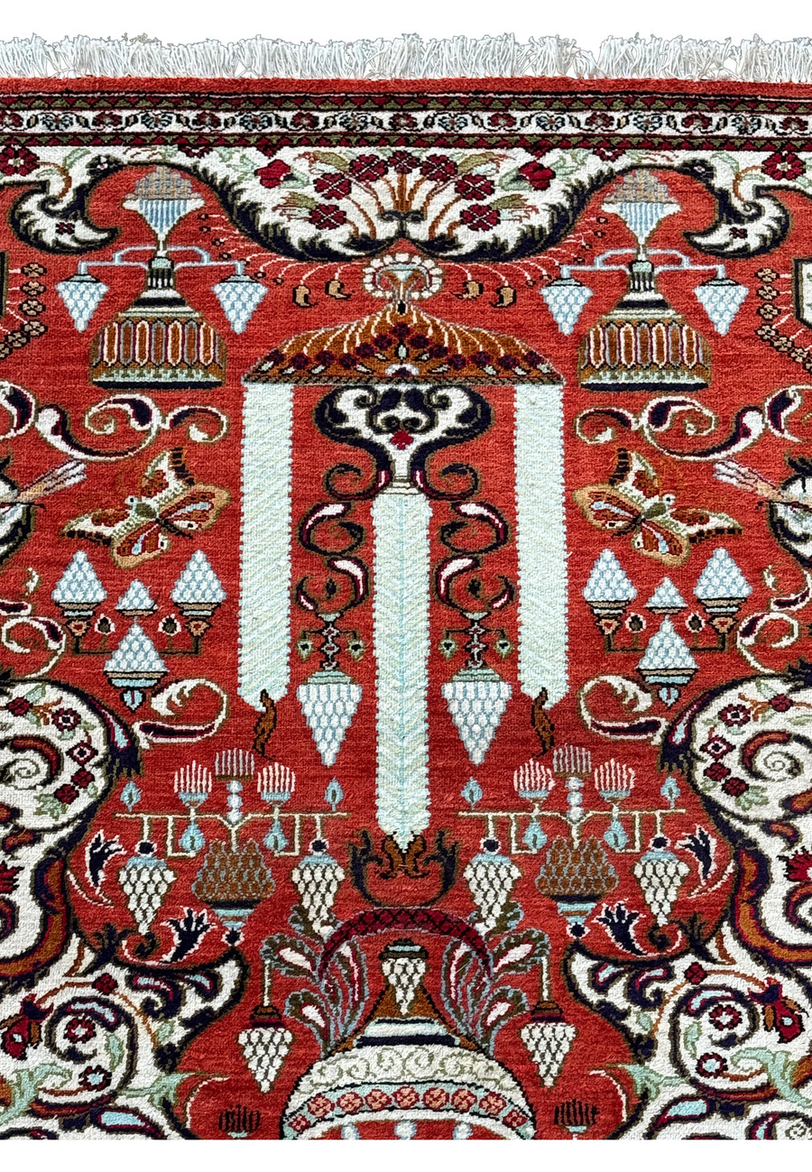 Partial view of a Persian Qum silk rug with focus on the elaborate geometric and floral border.