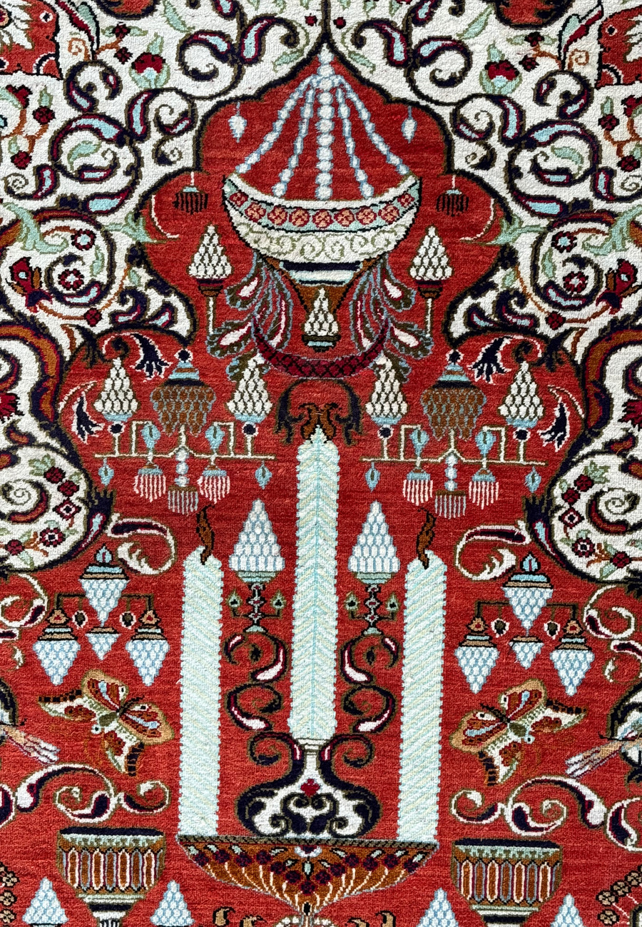 Close-up of a Persian Qum silk rug showcasing intricate patterns including cypress trees and florals