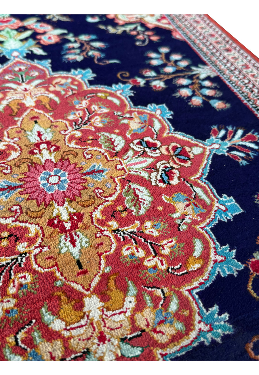 Angled view of a Persian Qum silk rug, emphasizing the depth of color and precision of the handwoven patterns