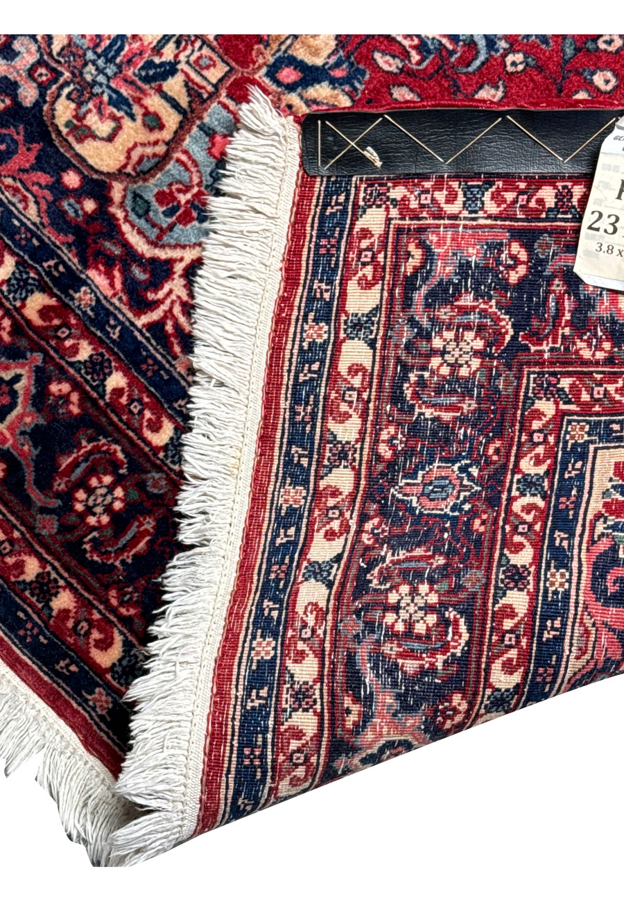 Persian Sarough rug corner showing the detailed border design and fringed edges, with a glimpse of the rug's label indicating size and origin