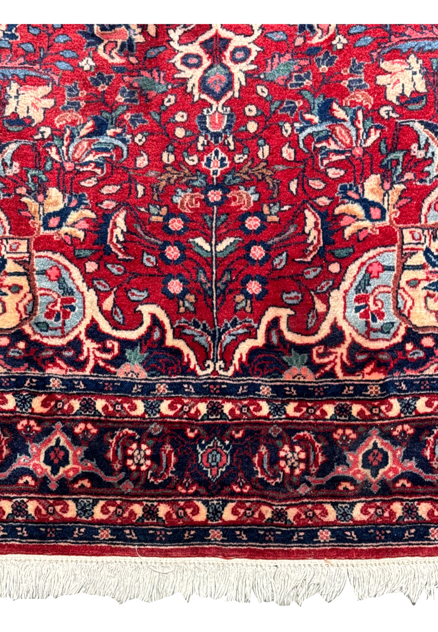 Upper part of a Persian Sarough rug focusing on the detailed floral motifs and border patterns in vivid reds and blues