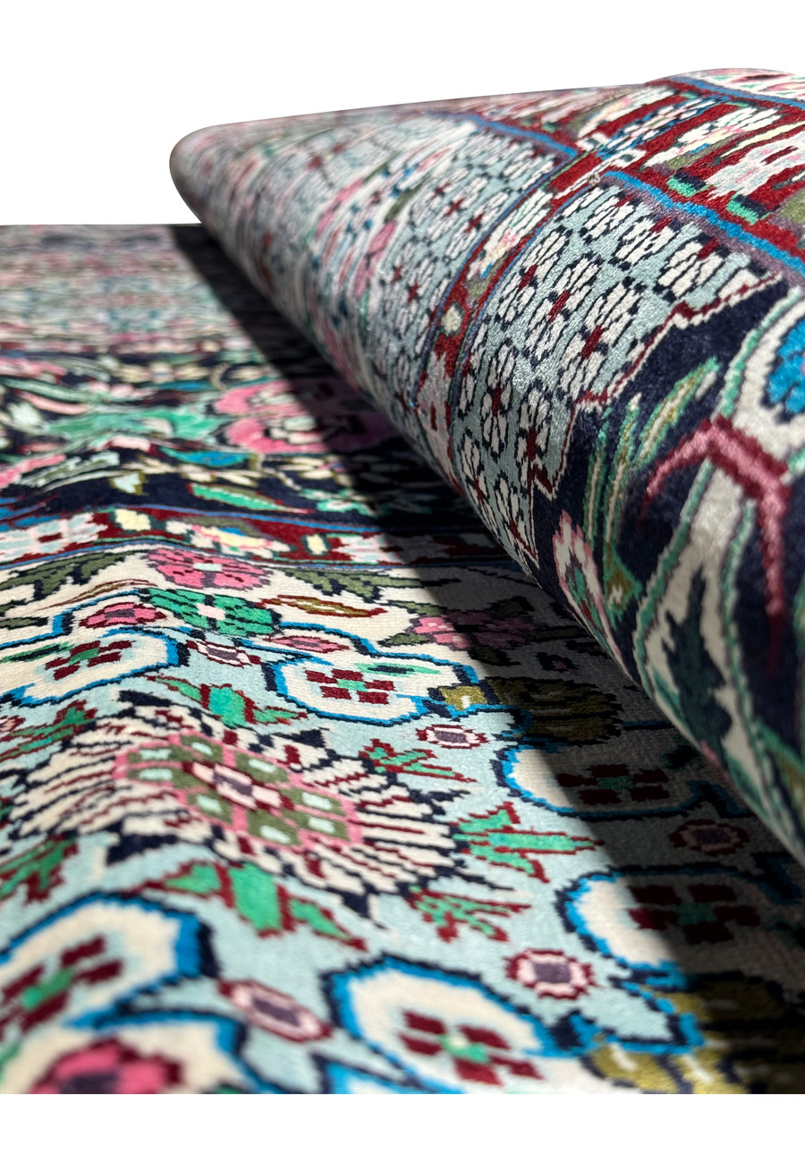 Angled view of a Persian Qum silk rug, showing the variation in color and pattern across the surface