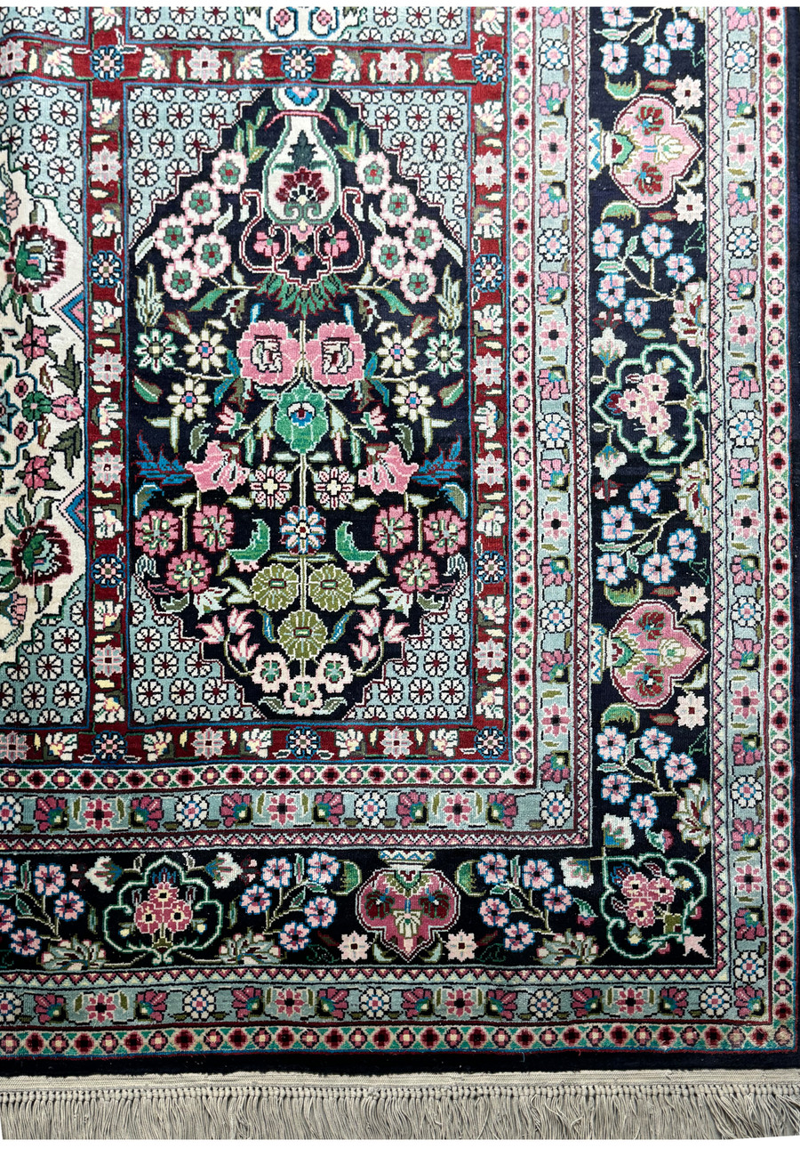 Corner detail of a Persian Qum silk rug, illustrating the delicate fringe and border pattern