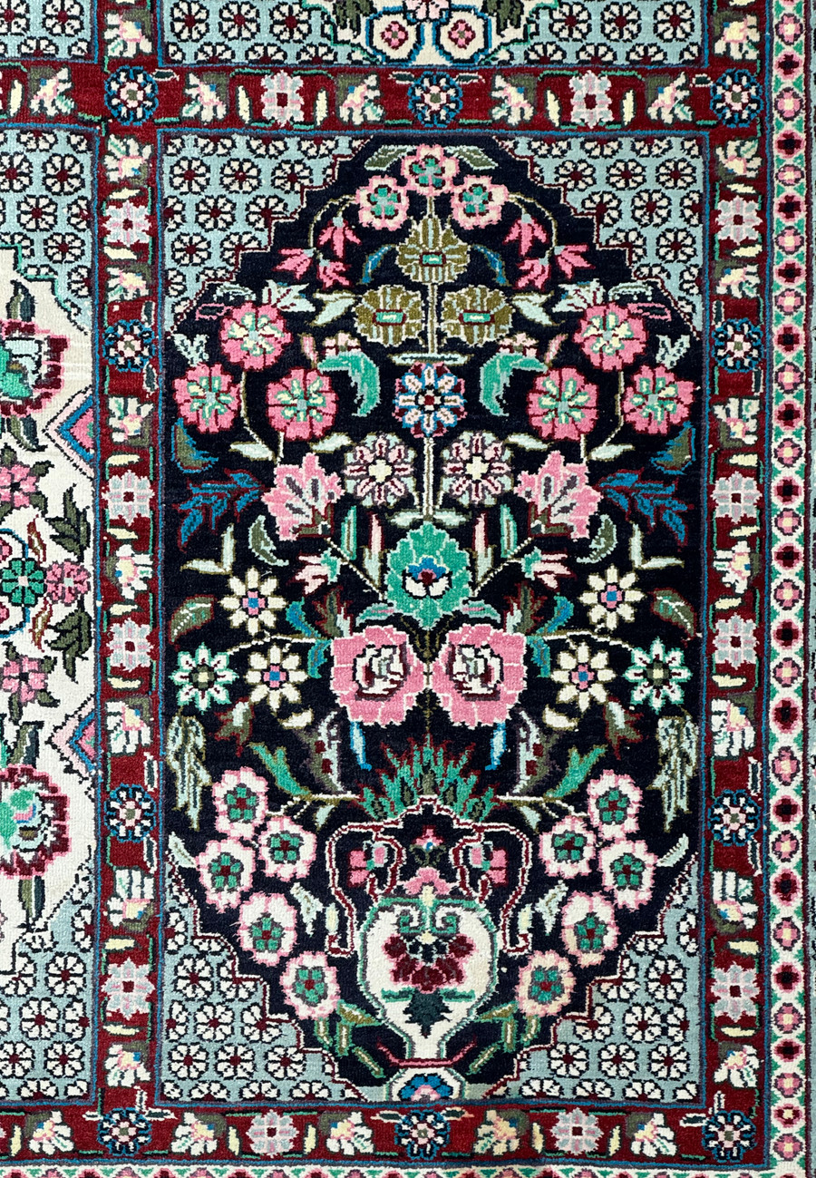 High-angle view of a Persian Qum silk rug, emphasizing the symmetry of floral patterns and border design