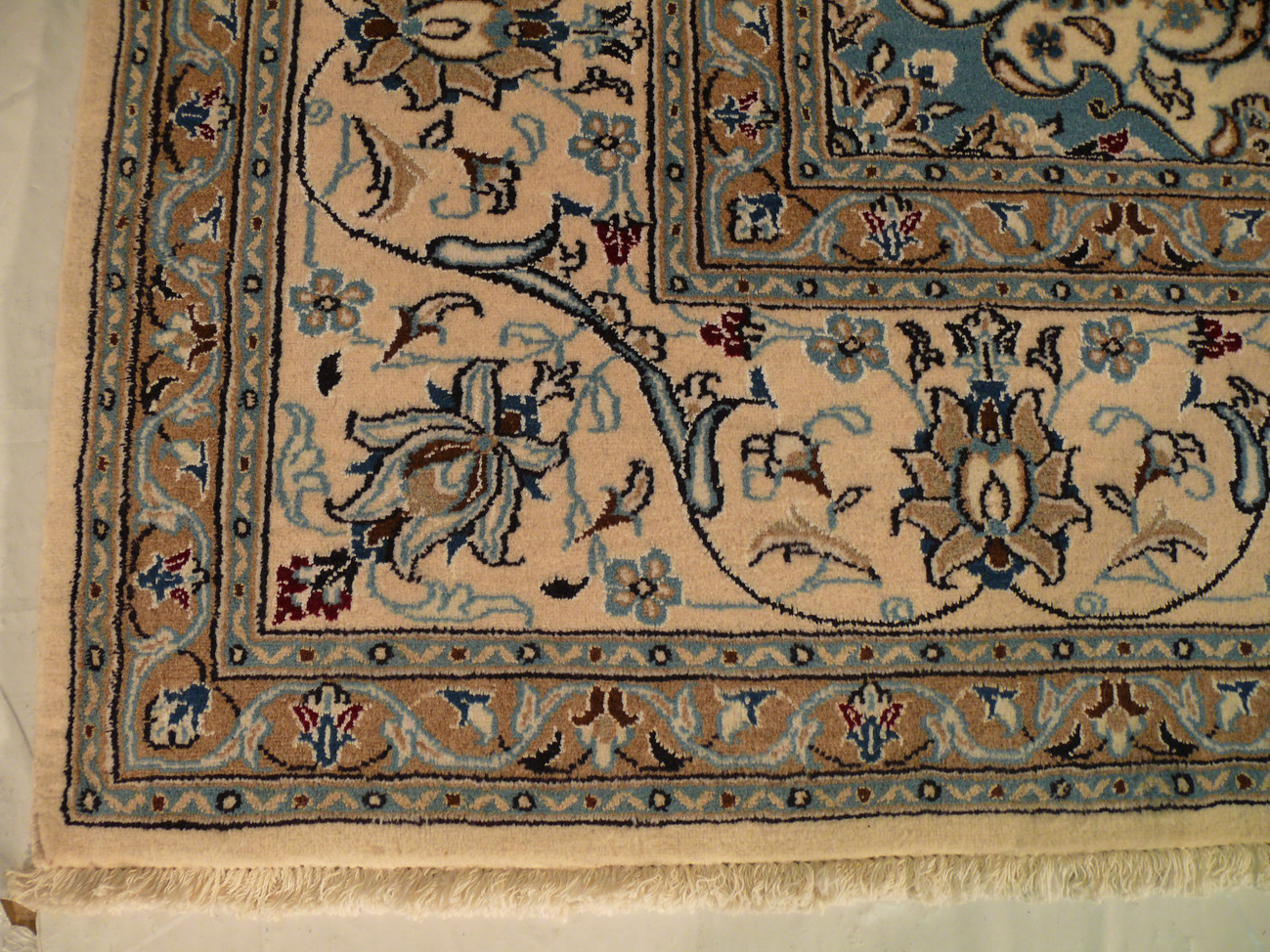 Edge view showing white outer border and clean handmade finish of Persian Nain rug