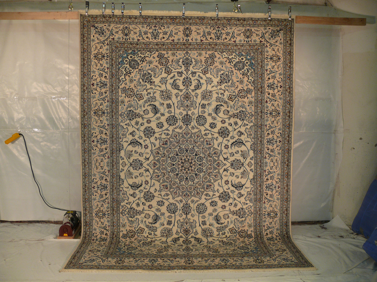 Handmade Persian Nain rug laid flat with beige field, navy medallion, and floral borders