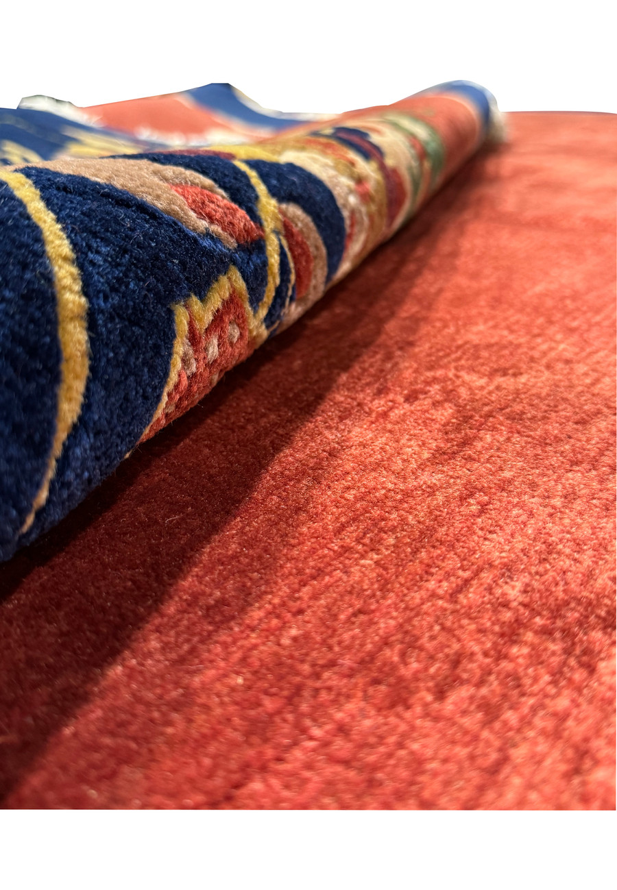 Close-up view of a portion of the modern Oriental Art Deco rug, with emphasis on the intricate floral design with gold, green, and pink on the navy border.