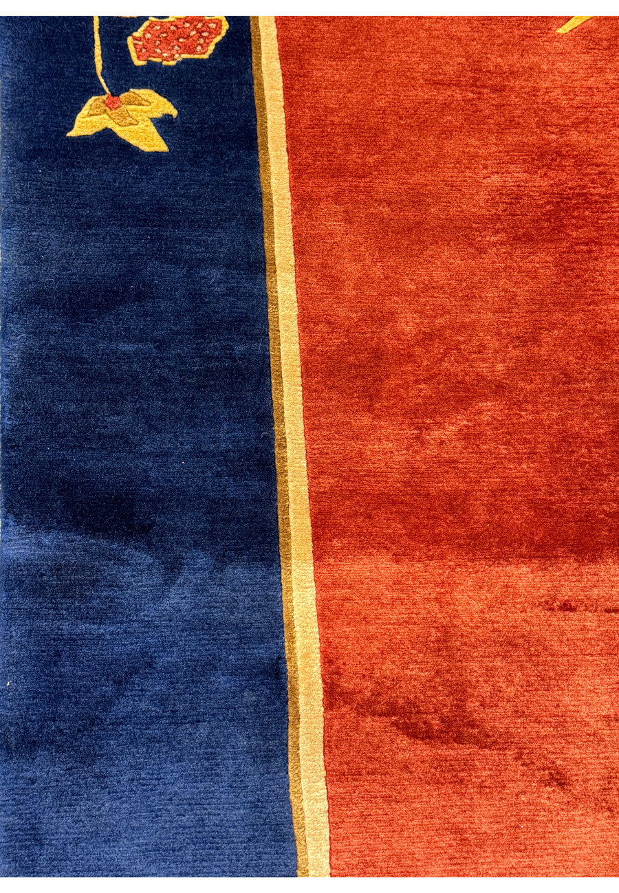 Close-up of the edge of the modern Oriental Art Deco rug, showing the fringe detail and the transition from the navy border to the burnt orange center.