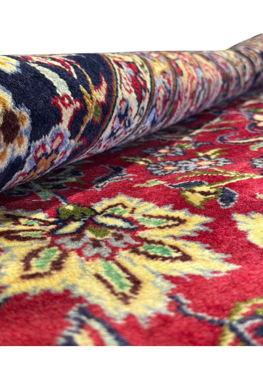 Close view of the rolled Persian Isfahan rug - Image showing the Persian Isfahan rug partially rolled, focusing on the weave patterns and color depth.