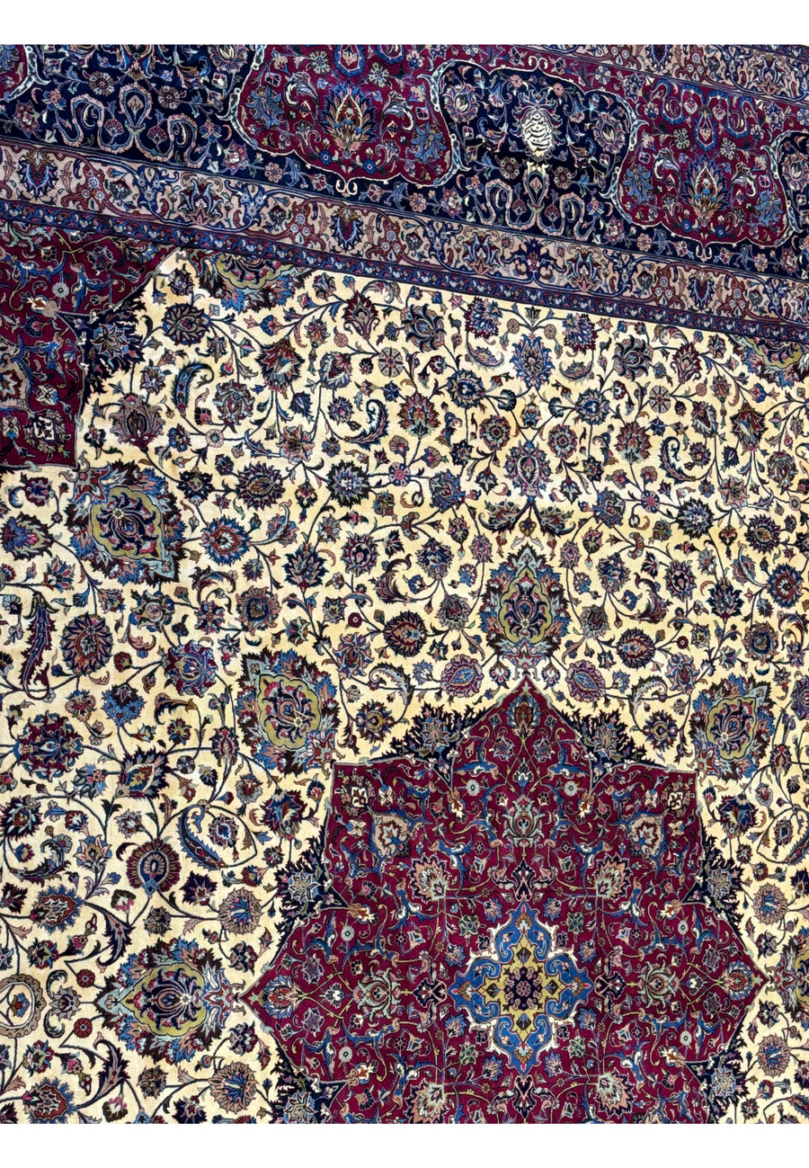 Zoomed-in view of the upper border and part of the central medallion of a Persian Mashad rug, highlighting the intricate patterns and rich colors, including blue, red, and ivory, with traditional Persian motifs