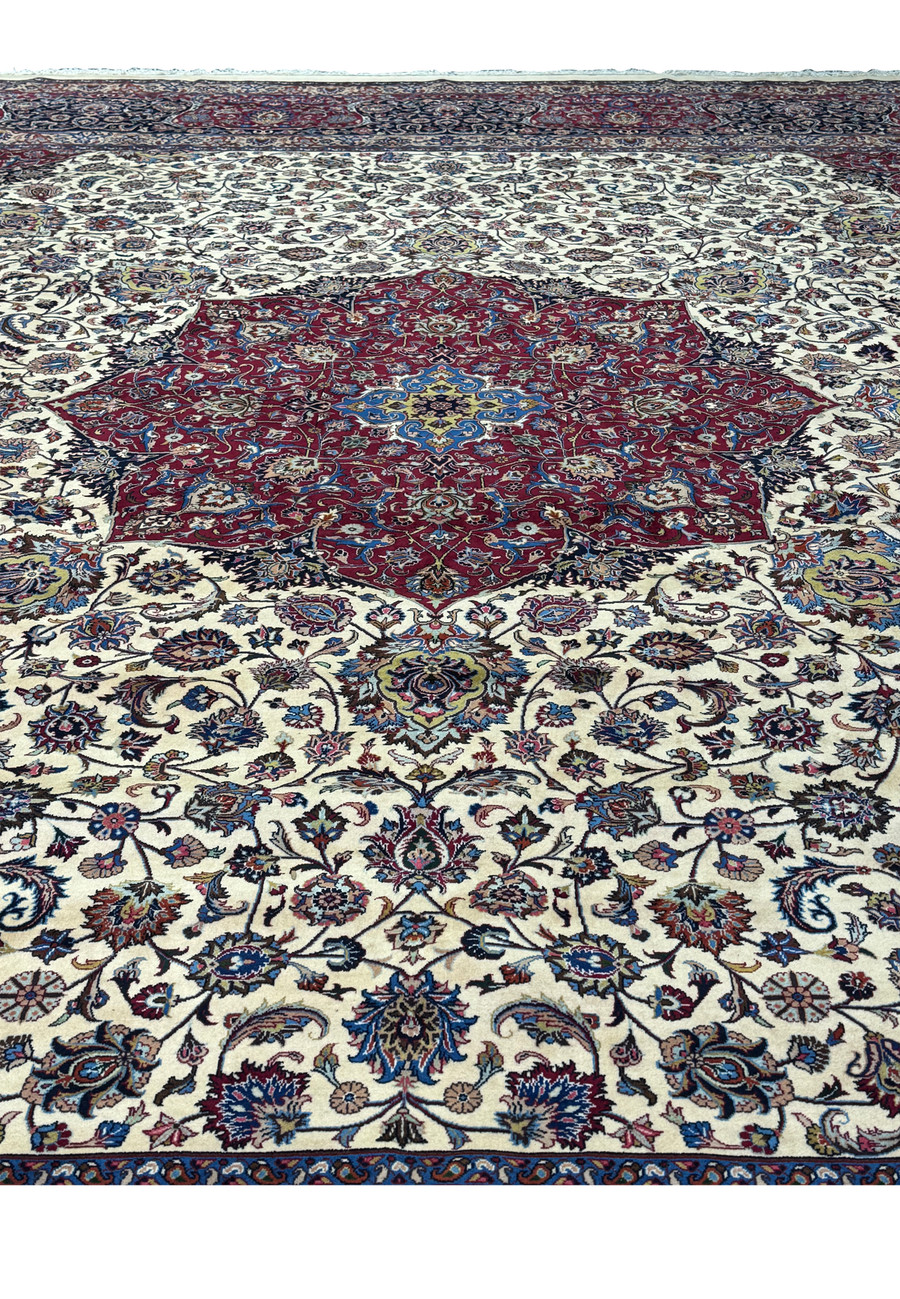 Full view of the central medallion of a Persian Mashad rug, displaying intricate floral and symmetrical patterns in rich red, blue, and gold, surrounded by detailed motifs and vibrant colors