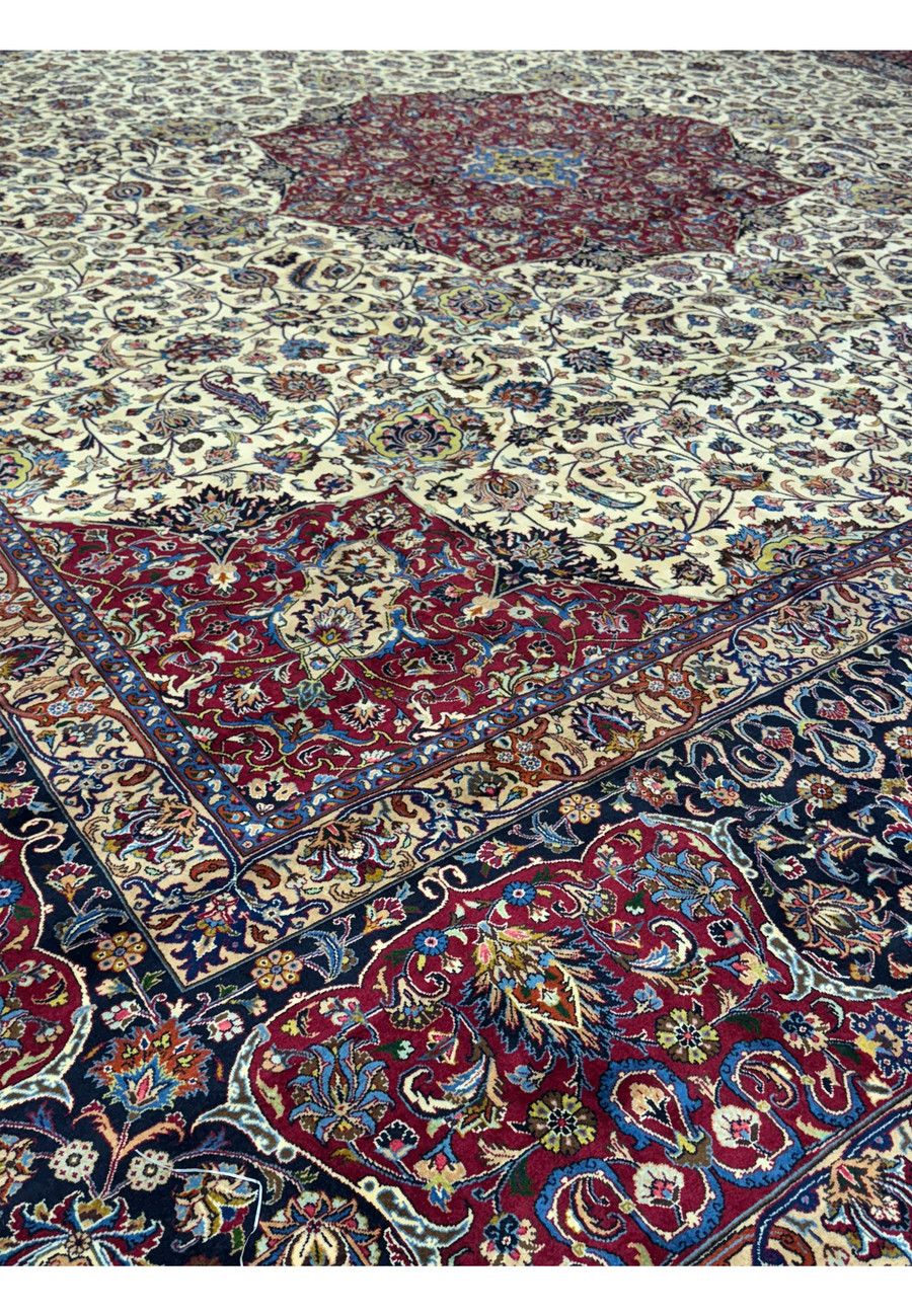 Close-up of the right border and part of the central medallion of a Persian Mashad rug, highlighting detailed floral and vine designs in deep red, blue, and beige, reflecting traditional Persian motifs and intricate craftsmanship