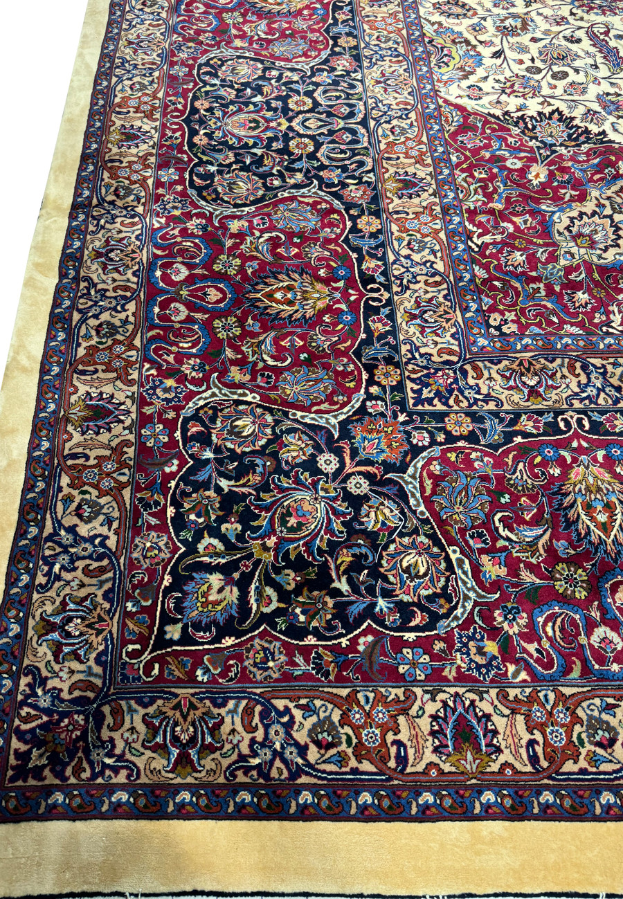 Focused view of the elaborate border on a Persian Mashad rug, displaying intricate floral patterns and vine scrolls in deep red, blue, and ivory, with meticulous weaving and traditional Persian design elements