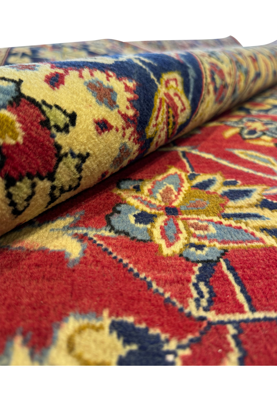 Close-up view of a Persian Isfahan rug, highlighting the luxurious texture and intricate floral patterns in red, blue, and gold, showcasing the fine craftsmanship and vibrant colors